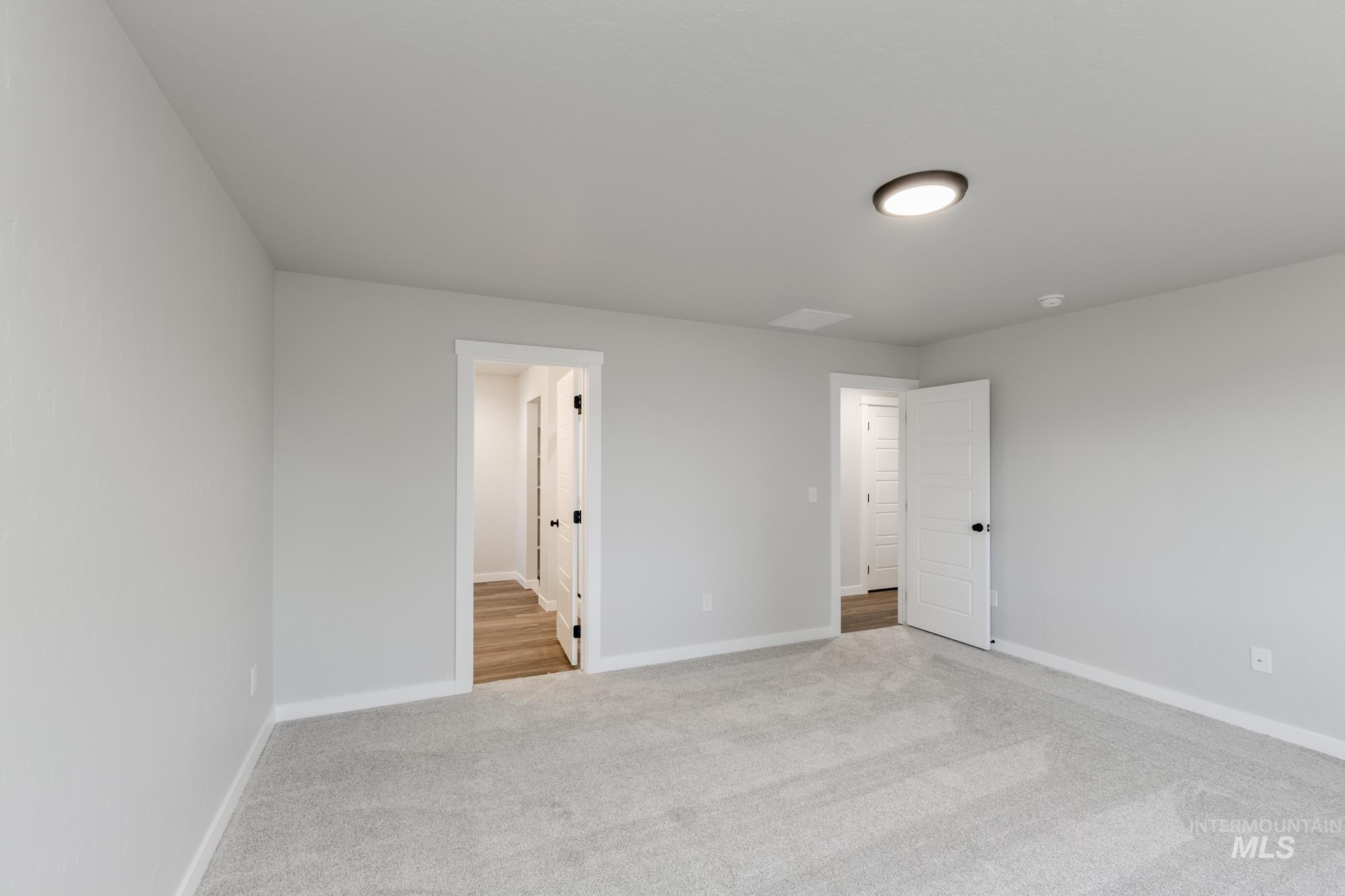 Unfurnished bedroom featuring light carpet and baseboards