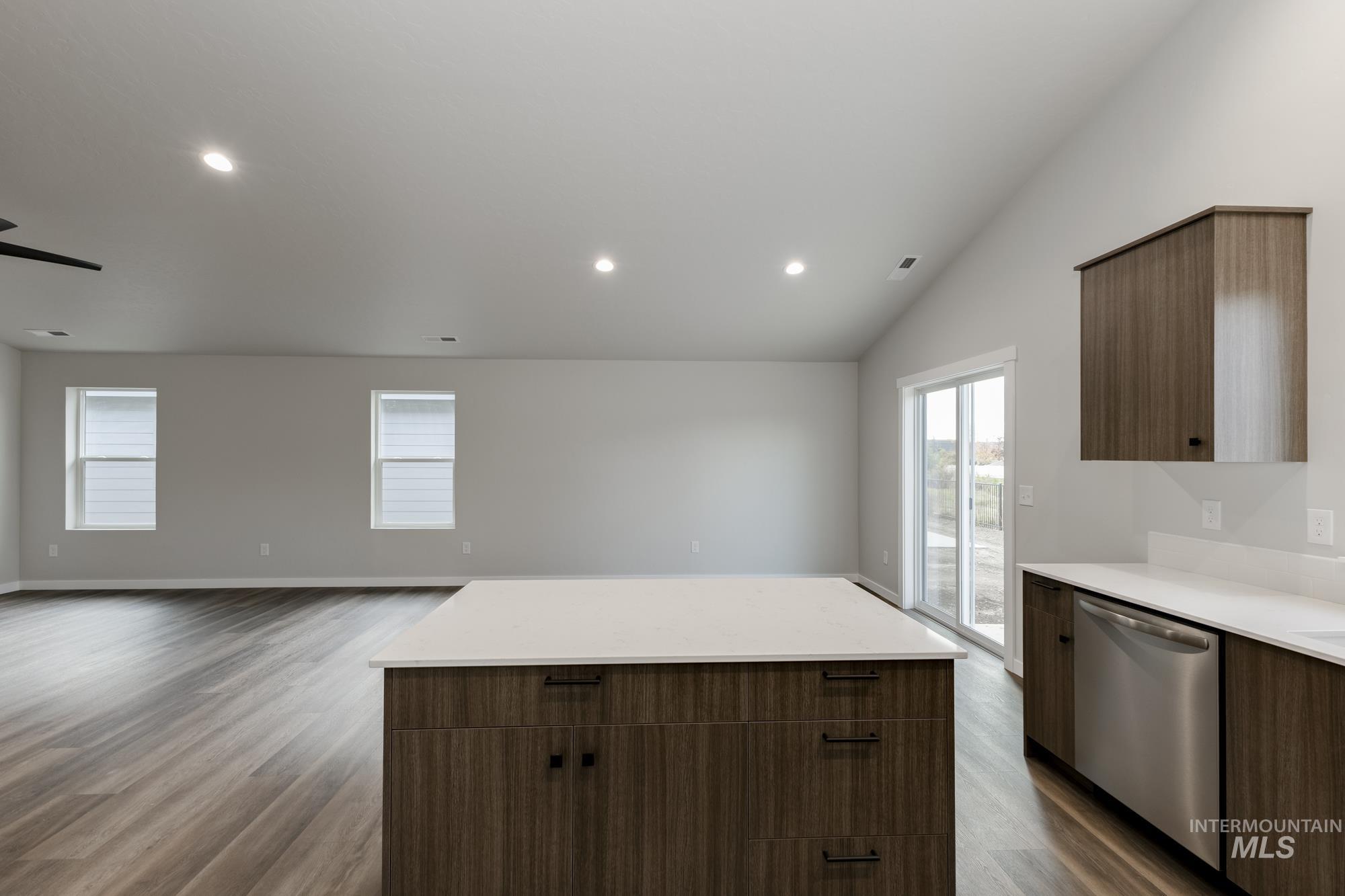 Kitchen with dark wood-type flooring, stainless steel dishwasher, a center island, modern cabinets, and recessed lighting