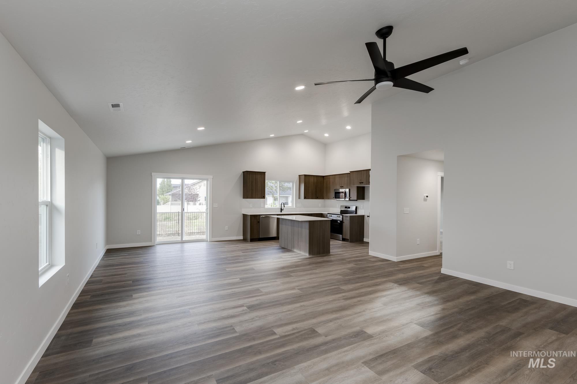 Unfurnished living room with high vaulted ceiling, dark wood finished floors, recessed lighting, and a ceiling fan