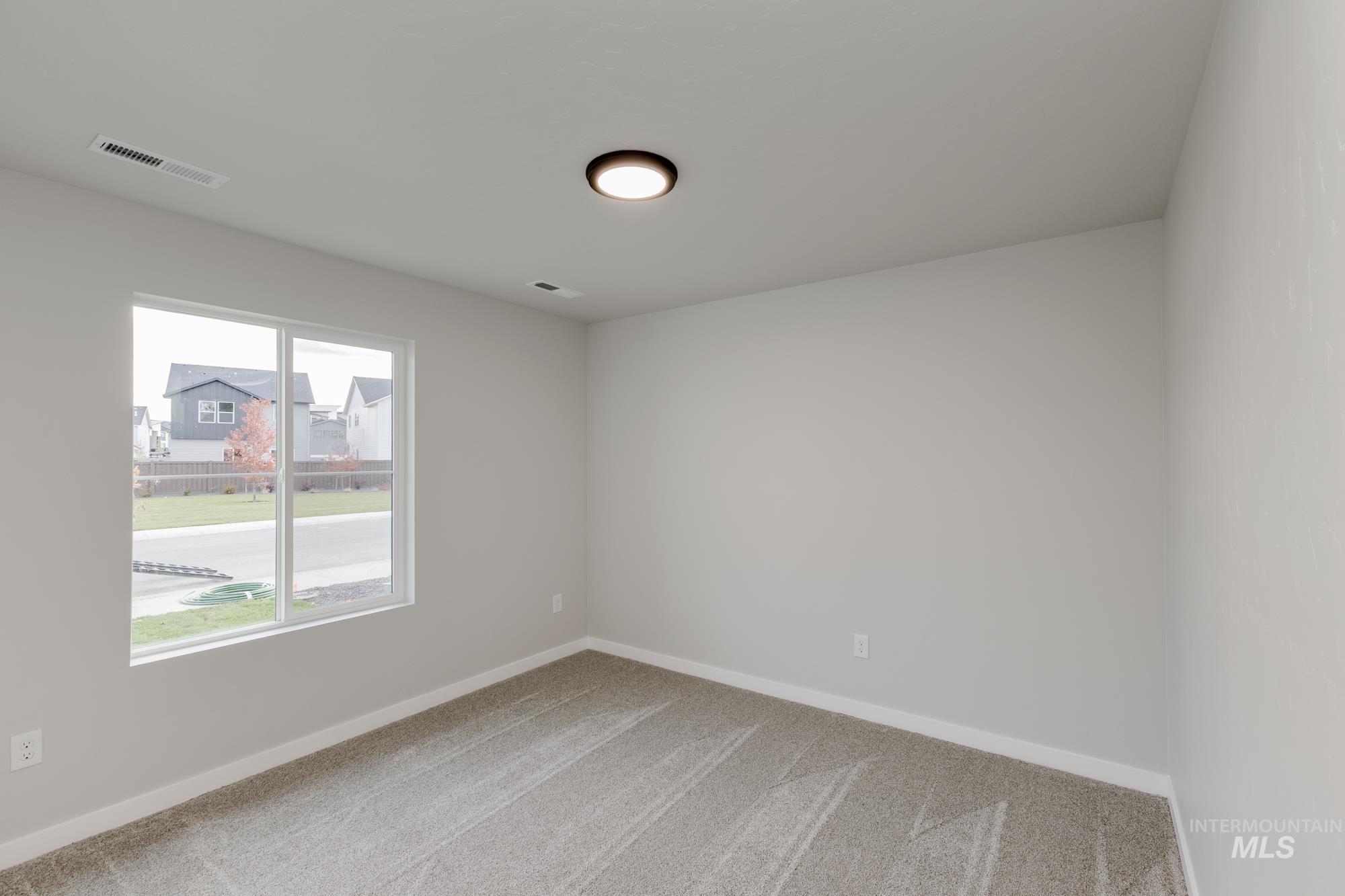 Spare room featuring light carpet and a residential view