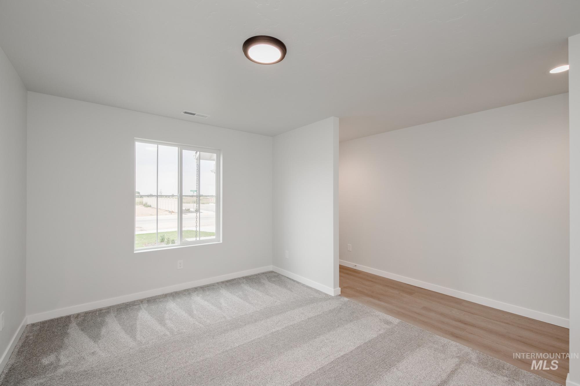 Empty room featuring light carpet and light wood-style floors