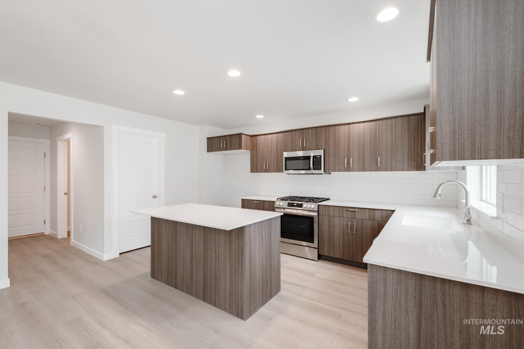 Kitchen featuring modern cabinets, stainless steel appliances, backsplash, a kitchen island, and recessed lighting