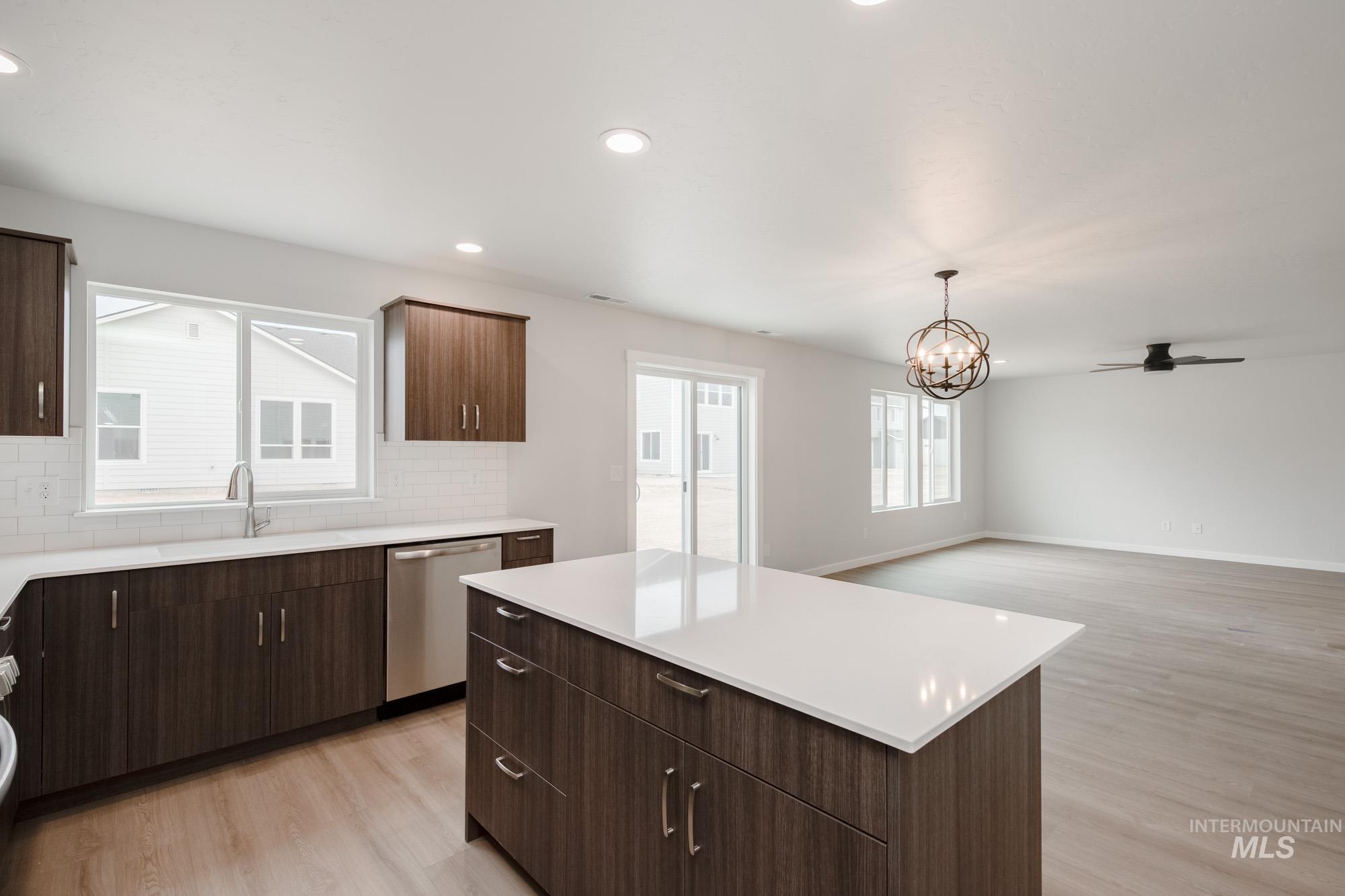 Kitchen featuring dark brown cabinets, light wood-type flooring, a center island, tasteful backsplash, and a ceiling fan