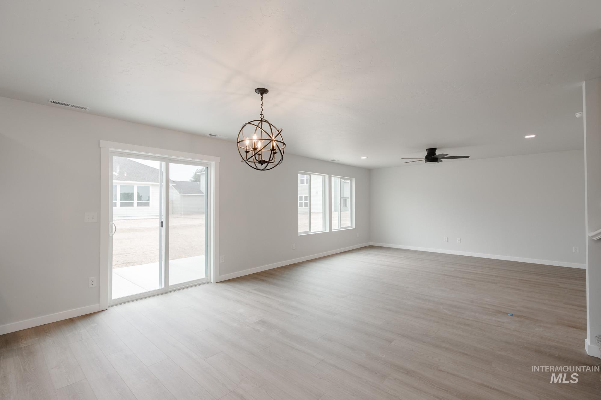 Unfurnished room with a chandelier, light wood-type flooring, ceiling fan, and recessed lighting