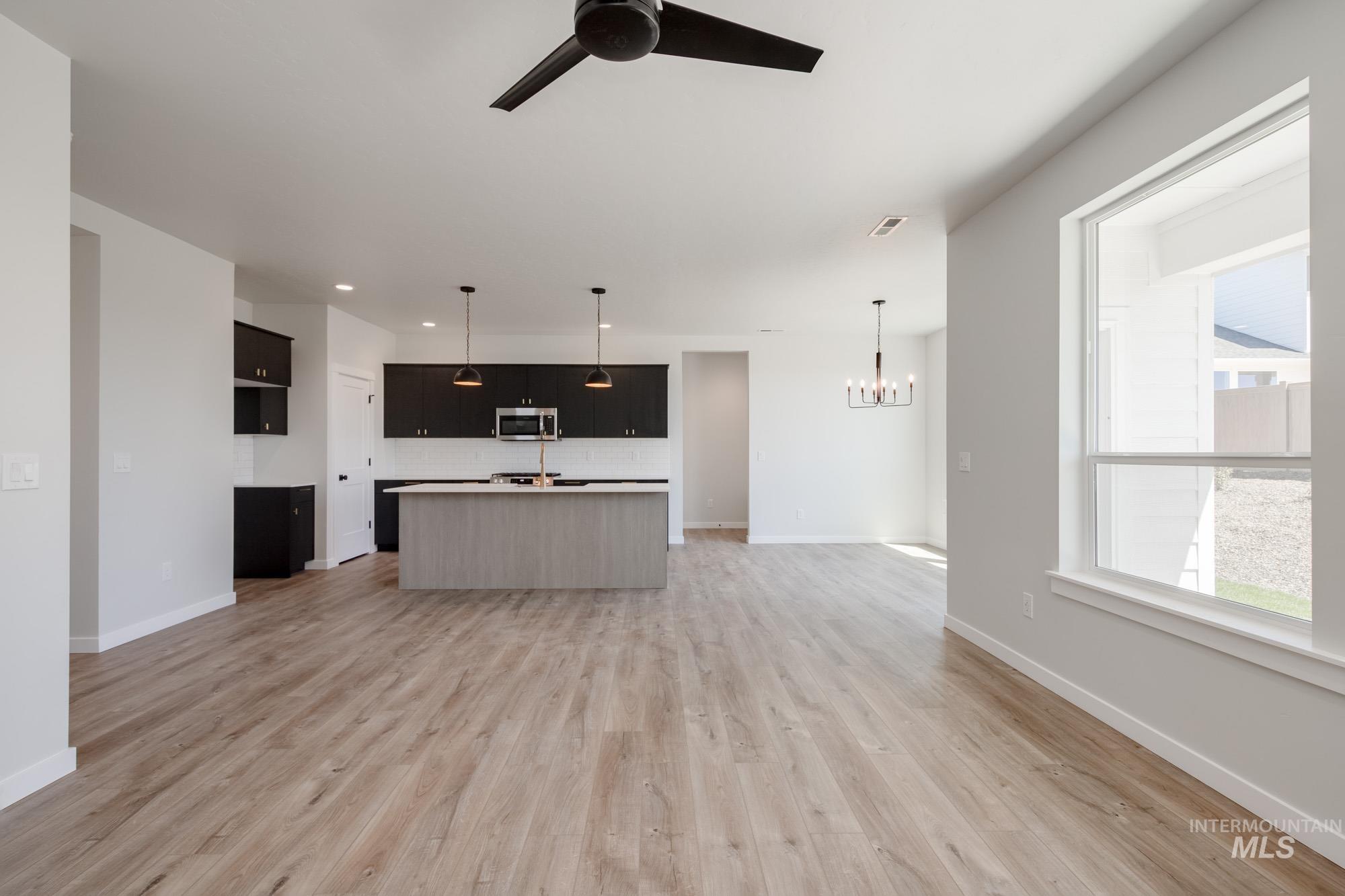 Kitchen featuring open floor plan, an island with sink, pendant lighting, tasteful backsplash, and recessed lighting