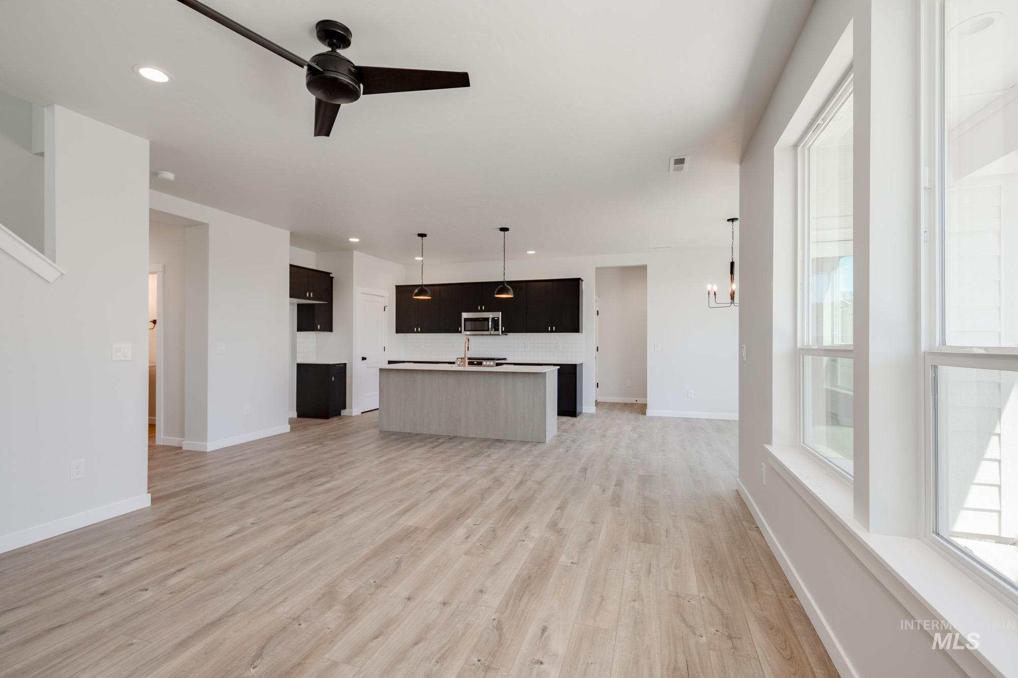 Unfurnished living room with light wood finished floors, ceiling fan, recessed lighting, and a chandelier