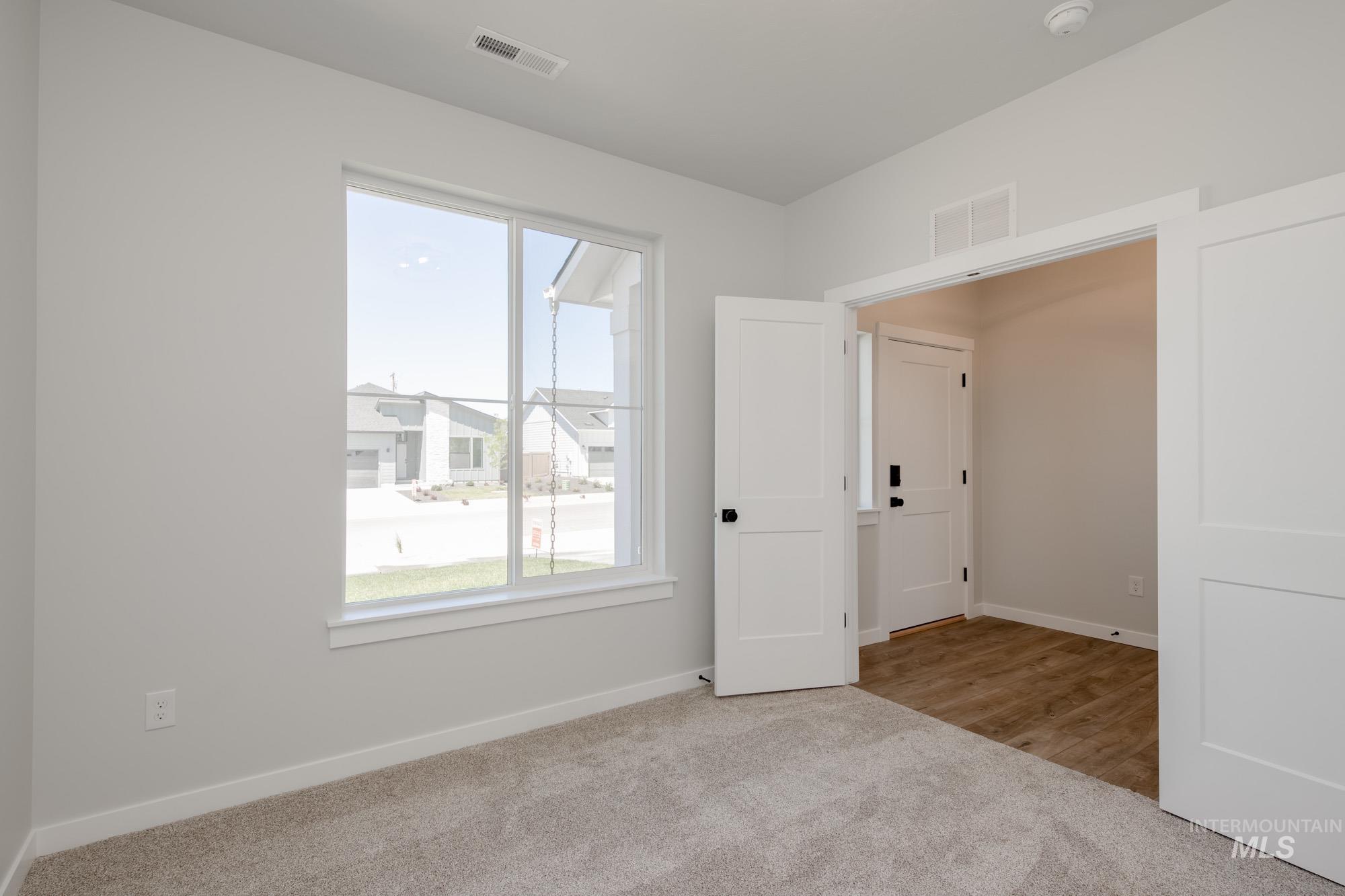 Unfurnished bedroom with light colored carpet and baseboards