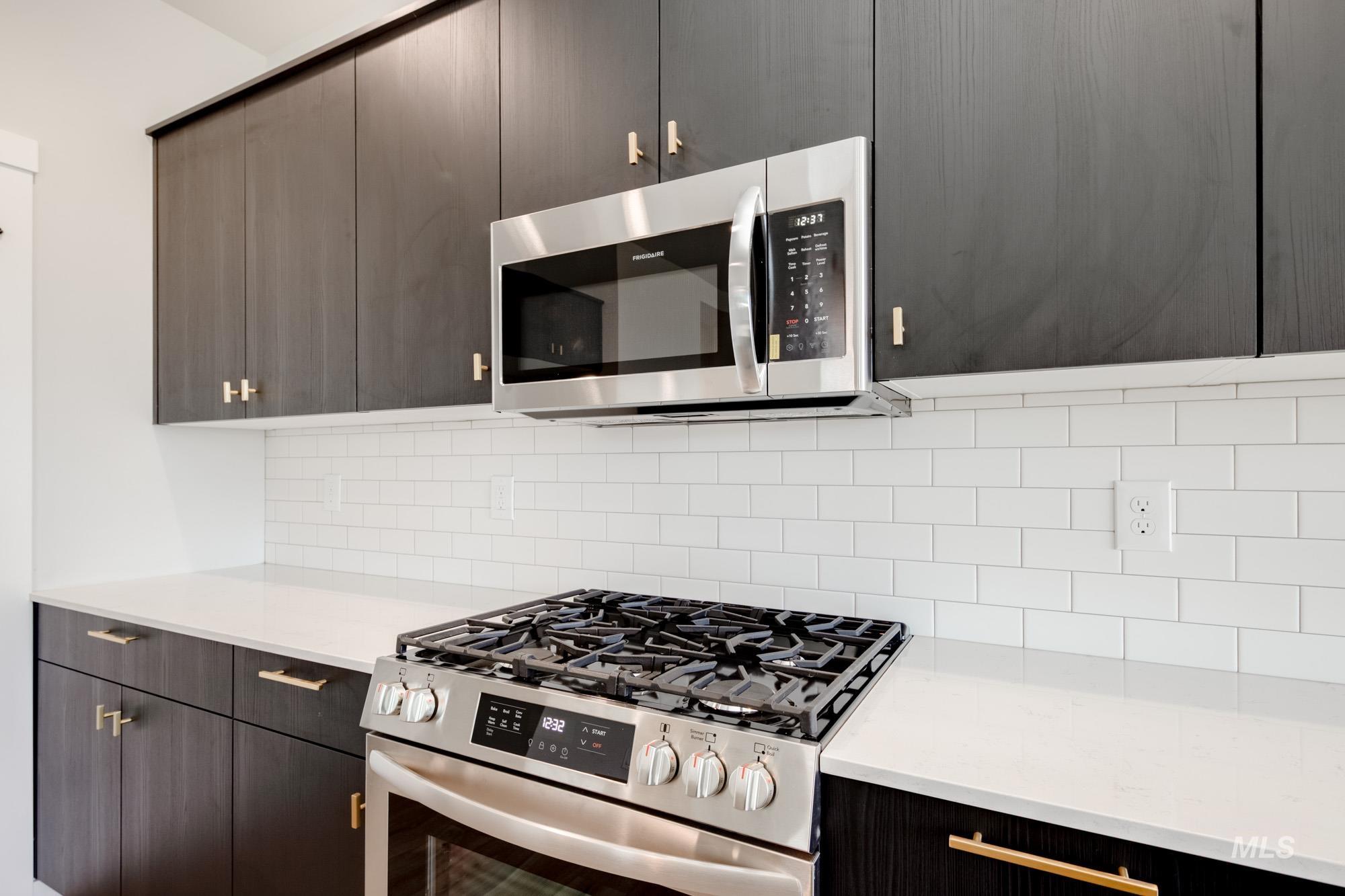Kitchen featuring appliances with stainless steel finishes, decorative backsplash, modern cabinets, and light stone countertops