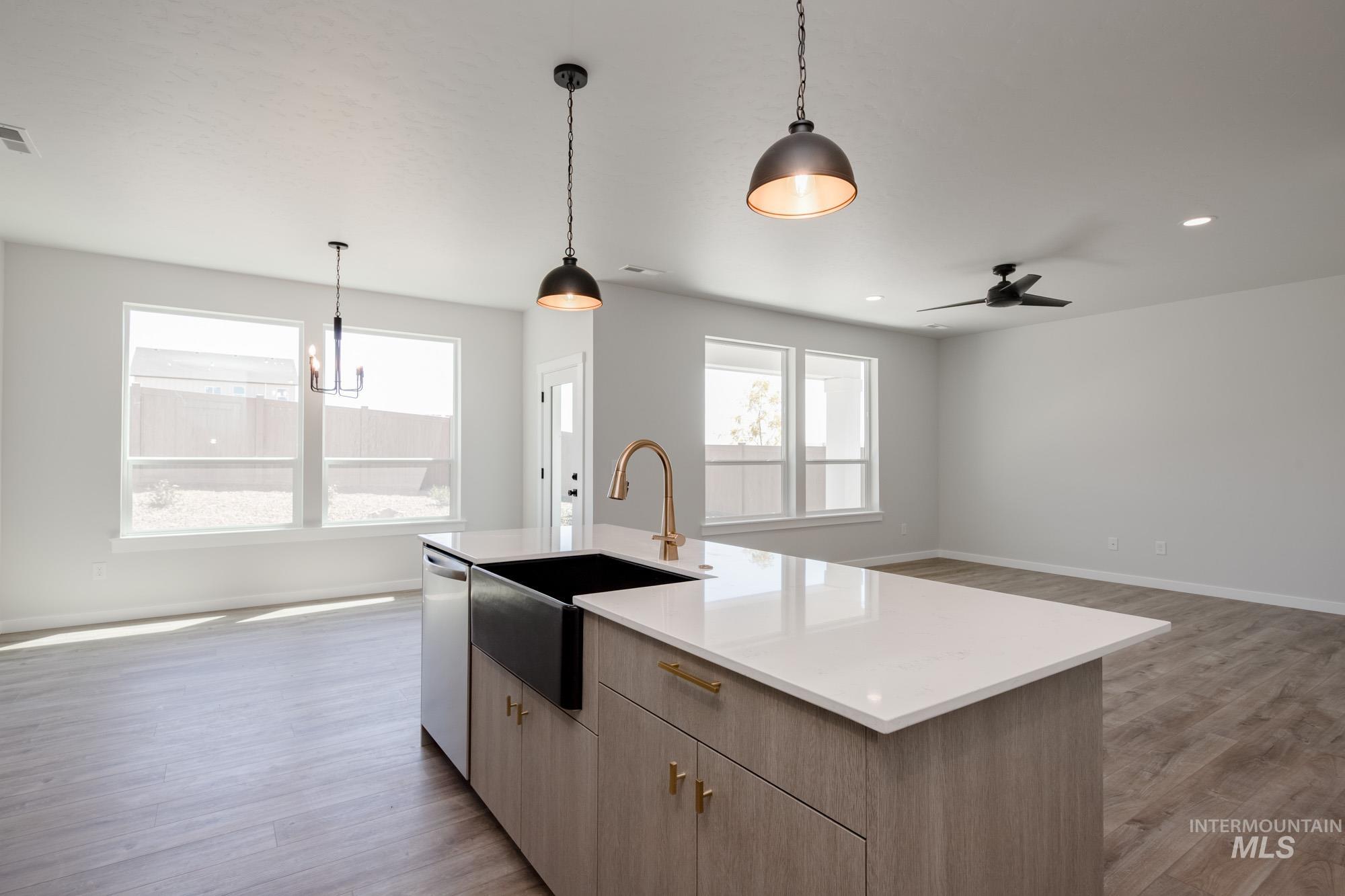 Kitchen featuring open floor plan, decorative light fixtures, light wood-style flooring, stainless steel dishwasher, and recessed lighting