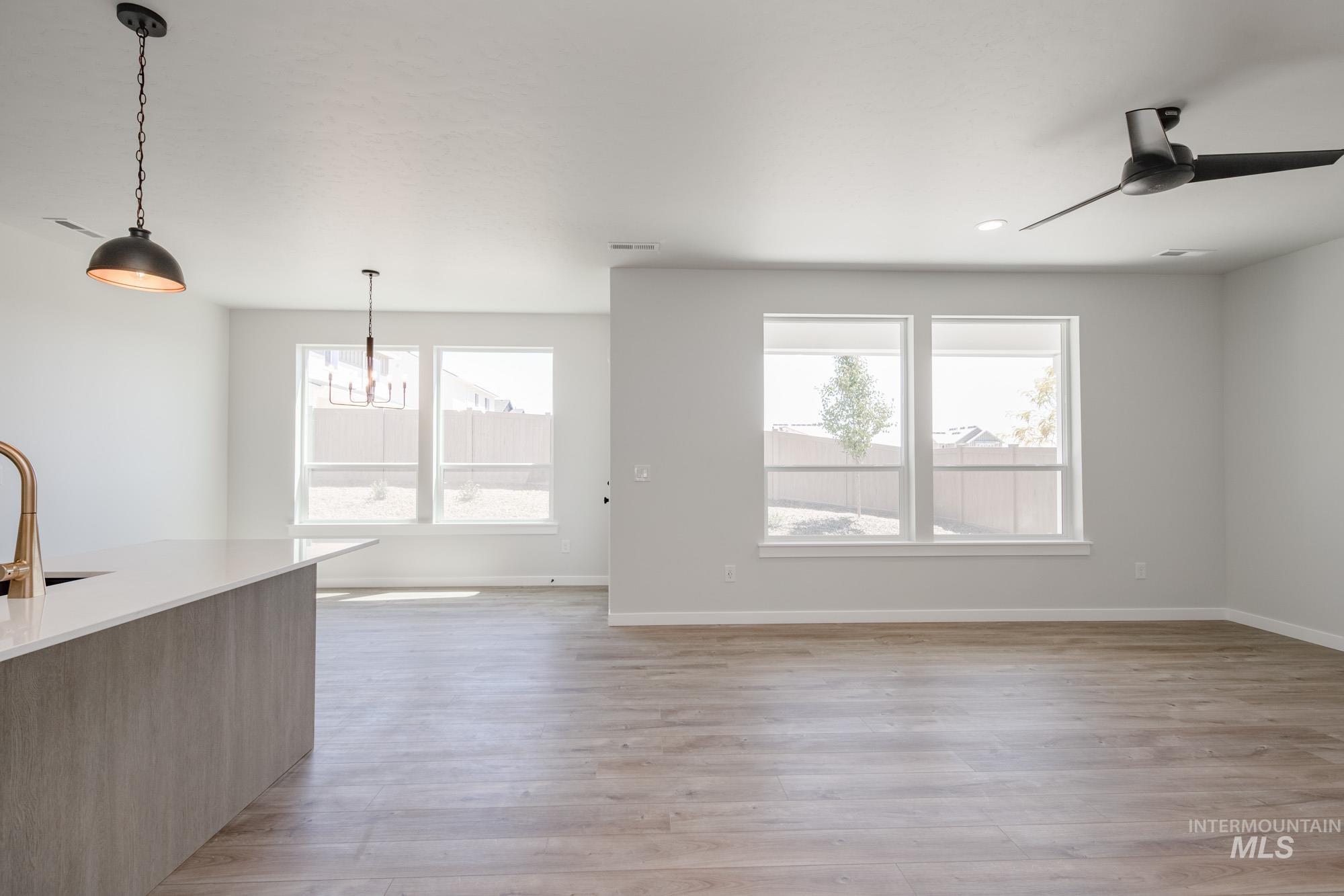 Unfurnished living room with light wood-style flooring, a chandelier, and a ceiling fan