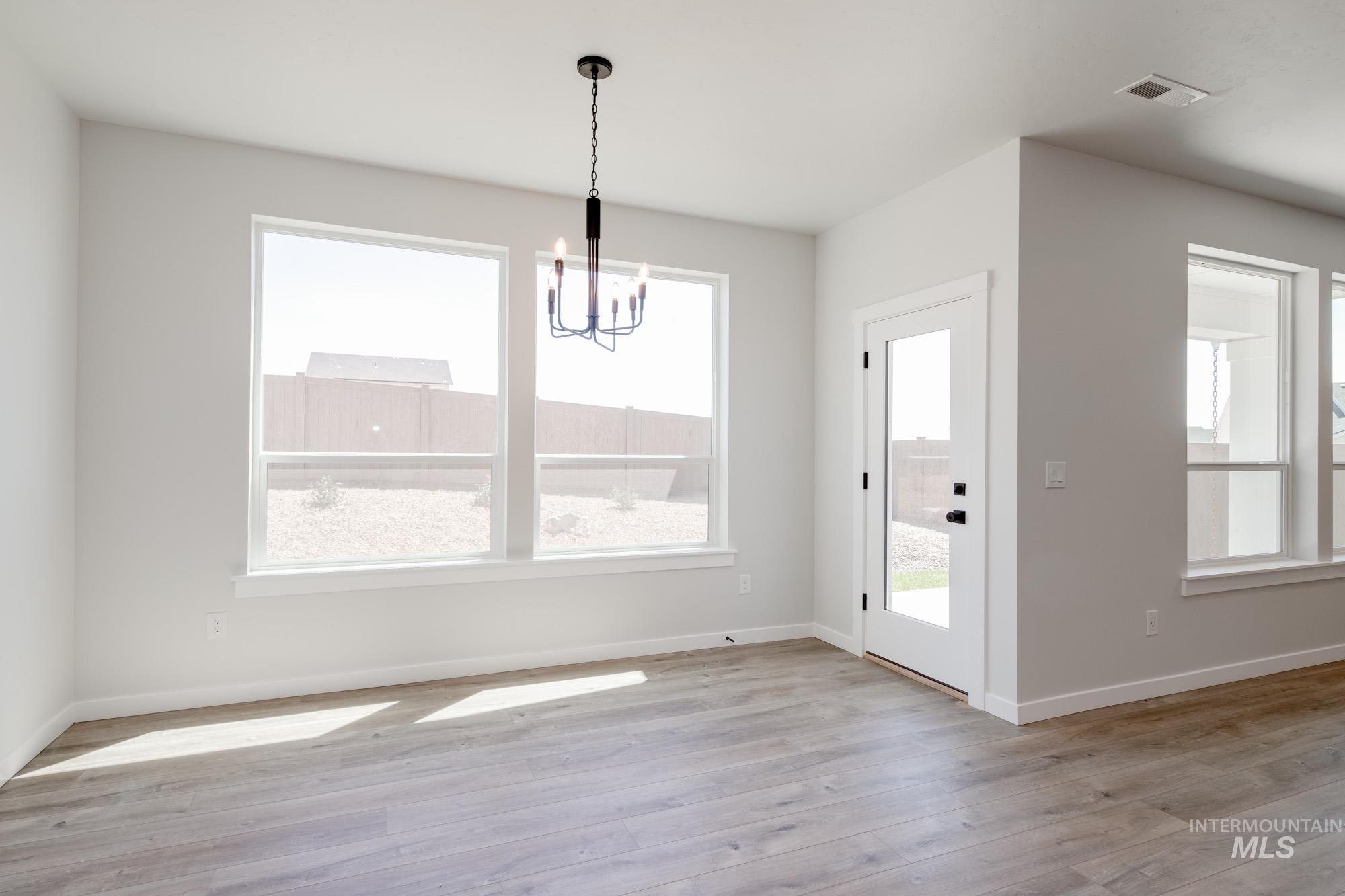 Unfurnished dining area with a chandelier and light wood-type flooring