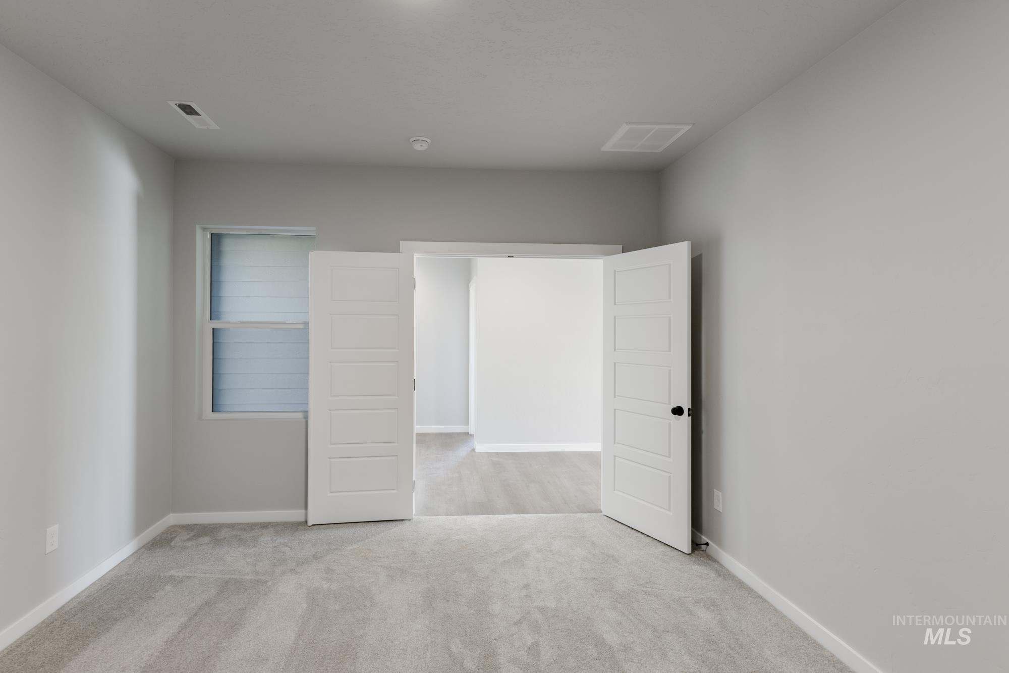Unfurnished bedroom featuring light colored carpet and baseboards