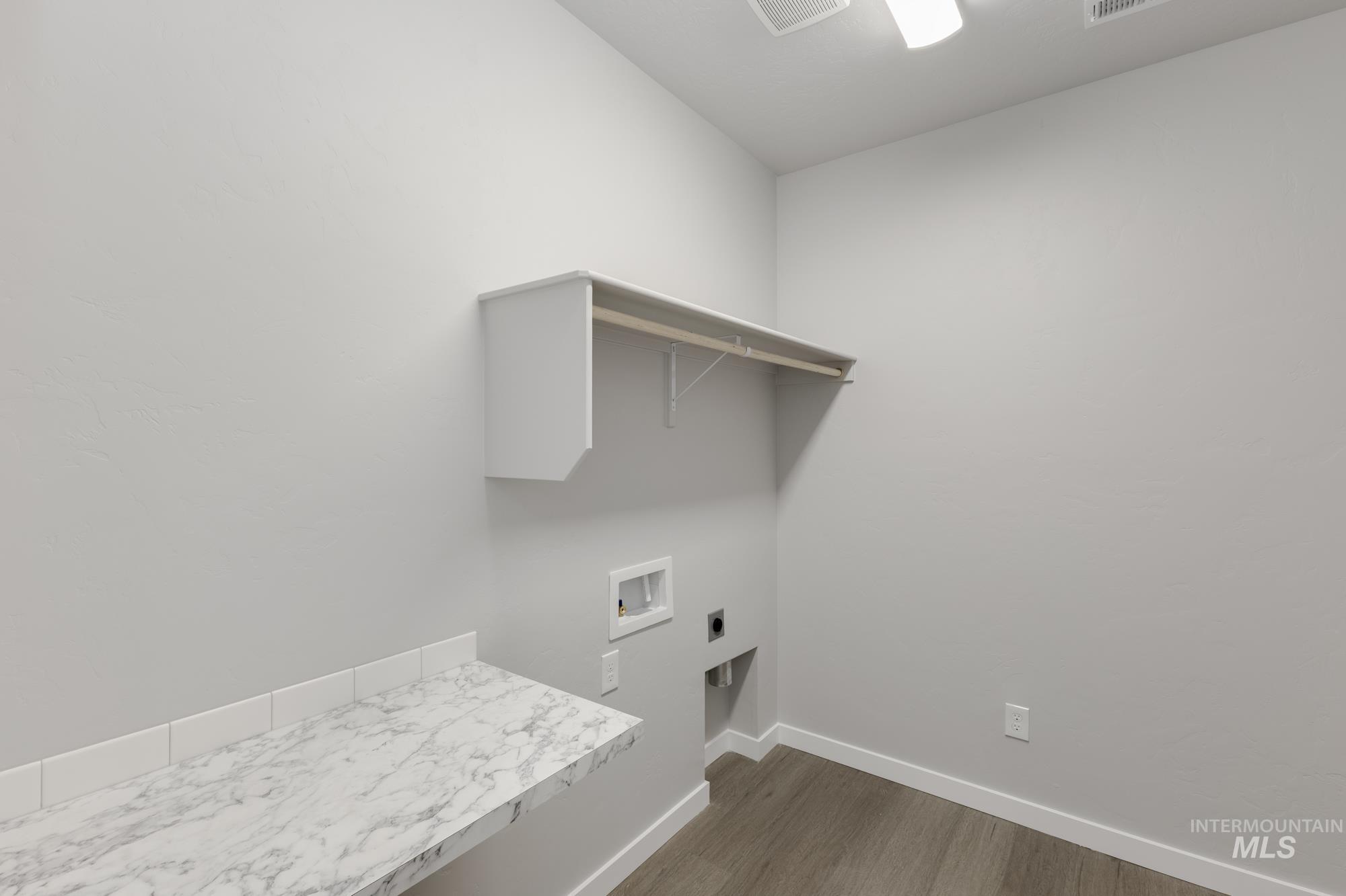 Laundry area with dark wood-style floors, hookup for an electric dryer, and hookup for a washing machine