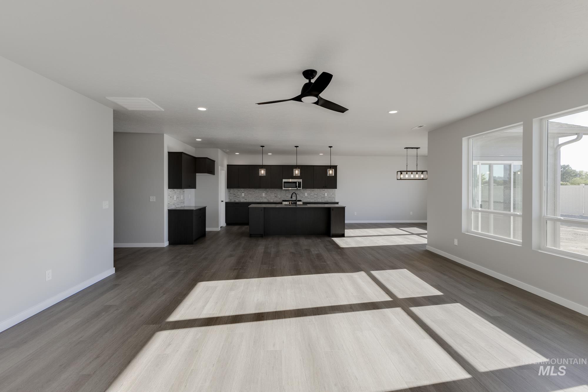 Unfurnished living room featuring ceiling fan, dark wood-style floors, and recessed lighting