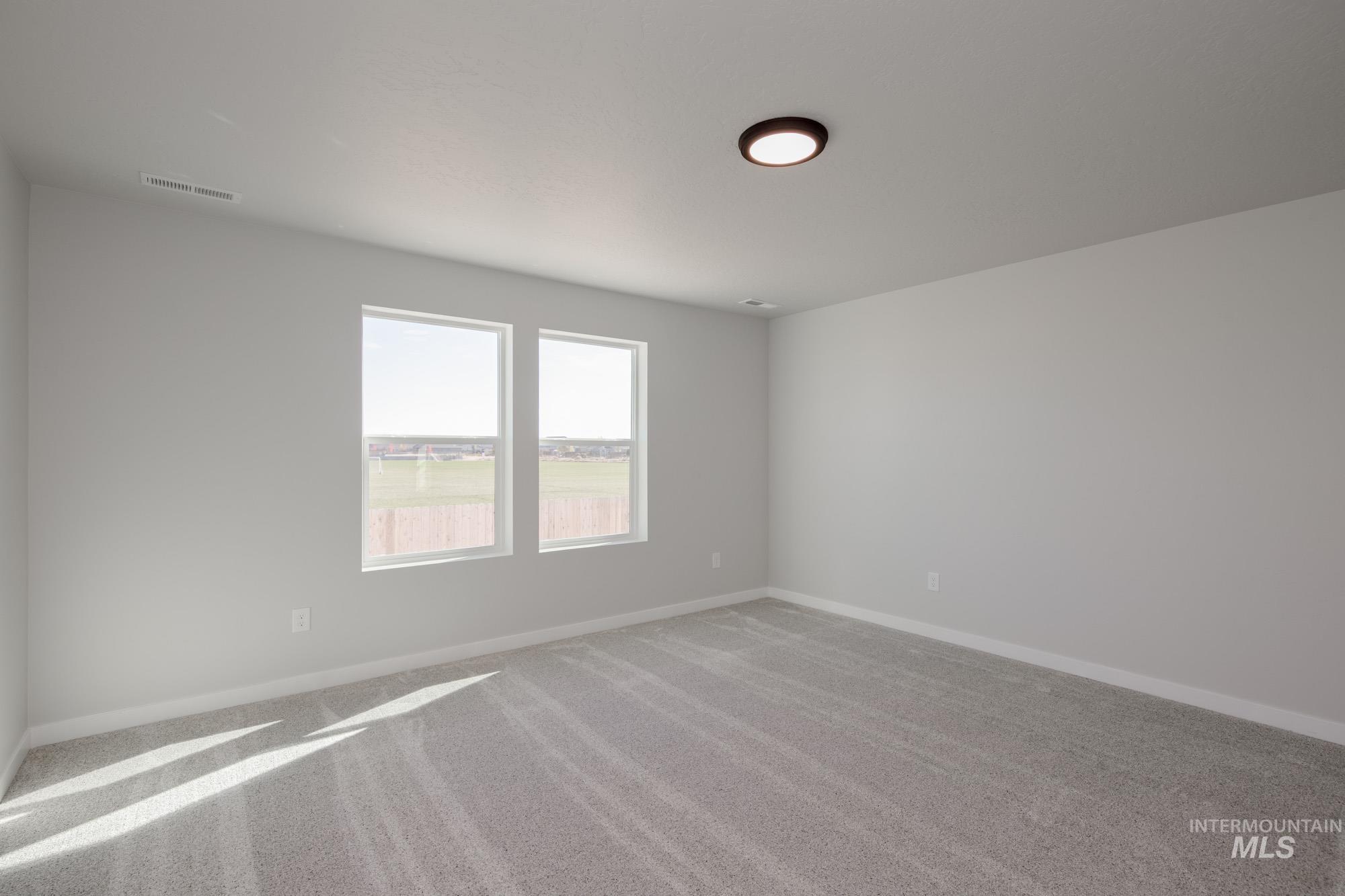 Carpeted spare room featuring baseboards