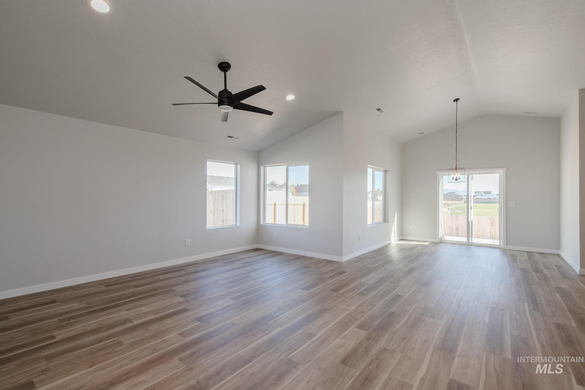 Unfurnished living room with vaulted ceiling, plenty of natural light, light wood finished floors, a ceiling fan, and recessed lighting