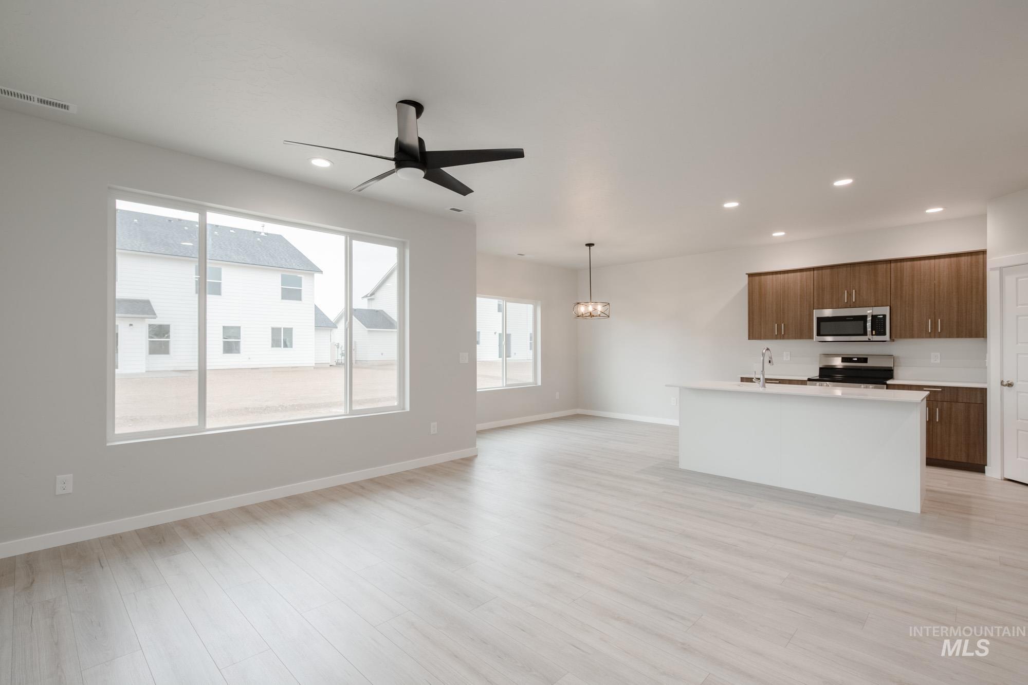 Kitchen with an island with sink, open floor plan, appliances with stainless steel finishes, pendant lighting, and recessed lighting