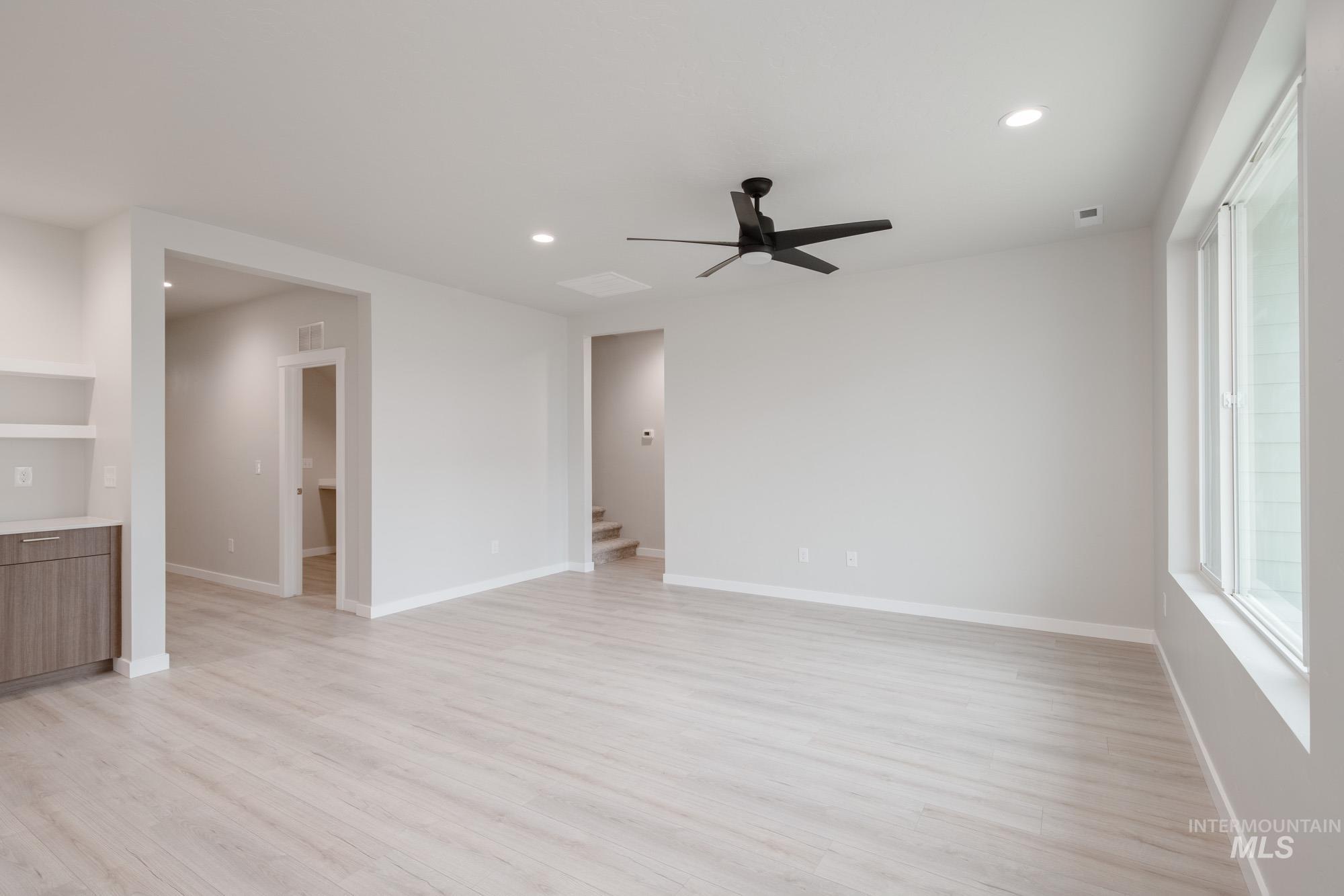 Spare room featuring light wood-type flooring, recessed lighting, a ceiling fan, and stairs