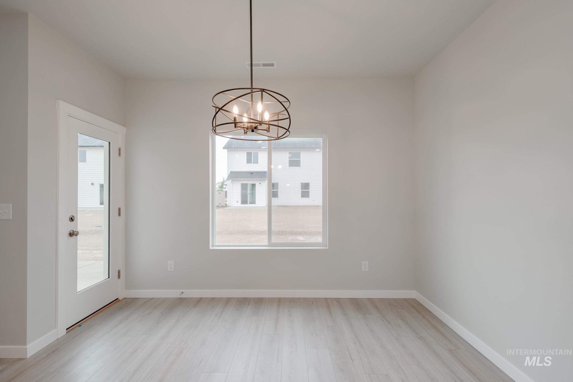 Unfurnished dining area featuring light wood finished floors and a chandelier
