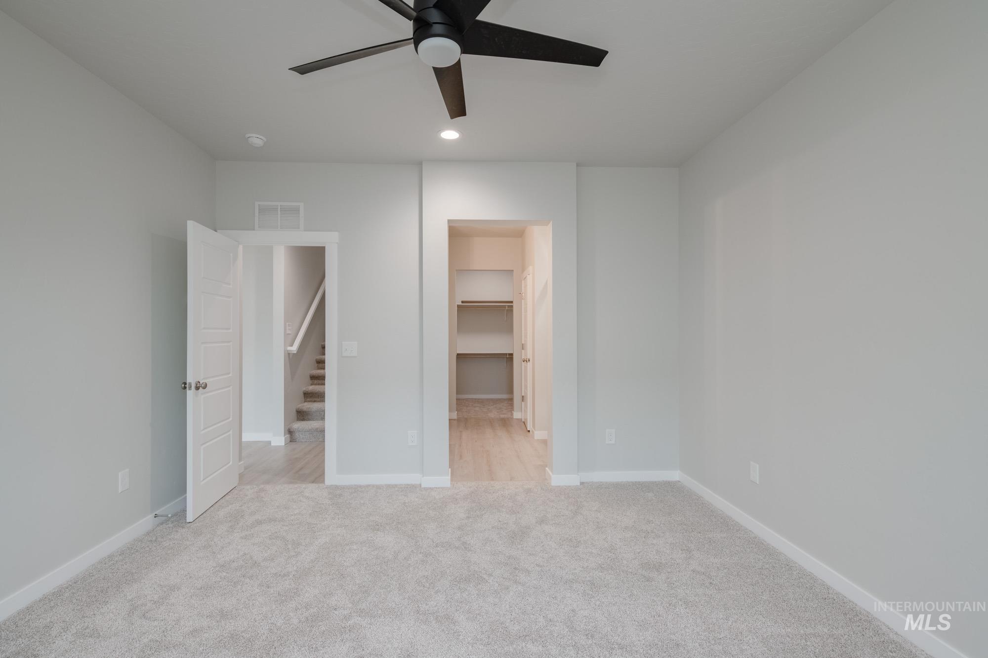 Unfurnished bedroom featuring a spacious closet, light carpet, recessed lighting, and a ceiling fan