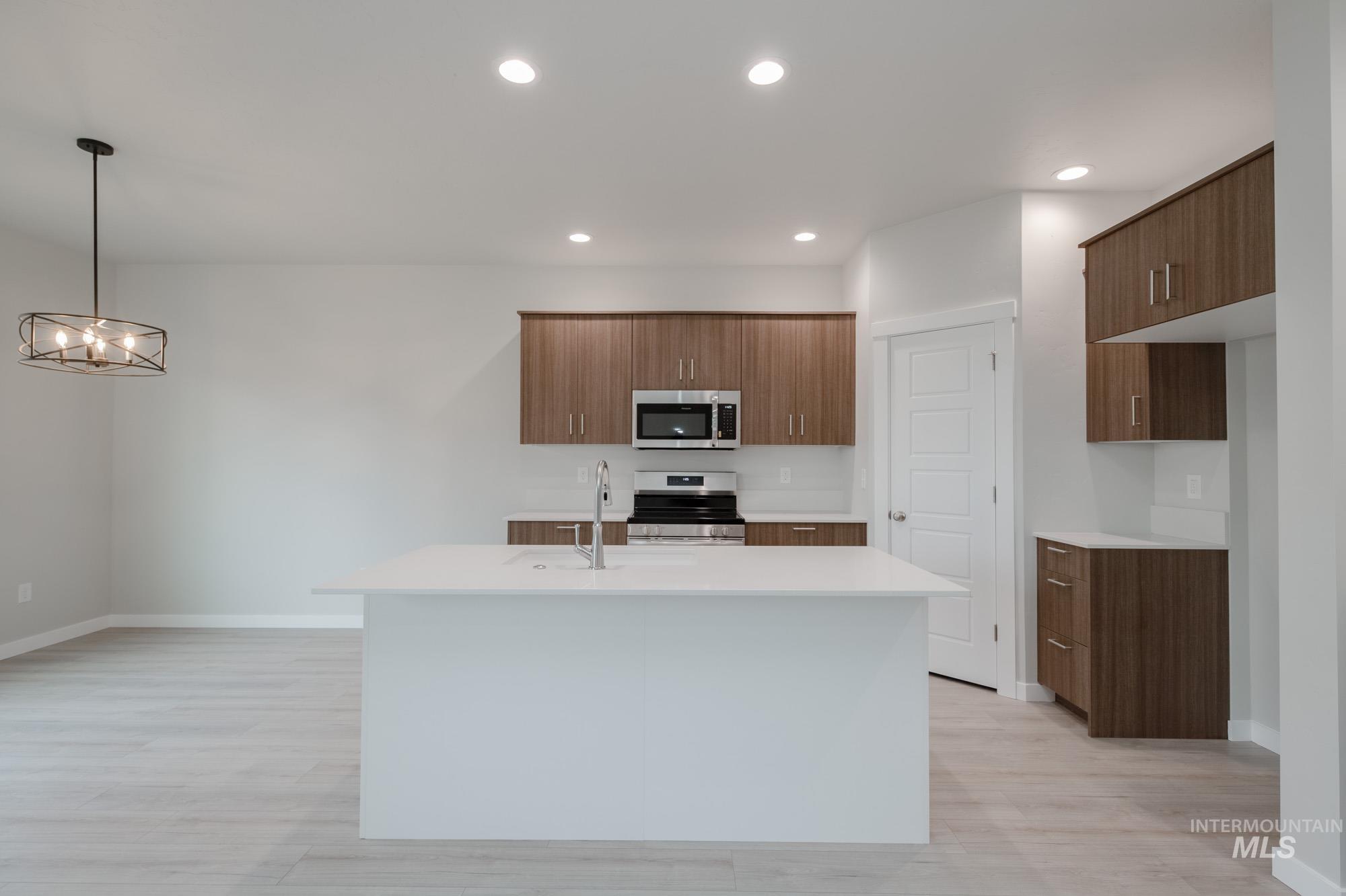 Kitchen with an island with sink, appliances with stainless steel finishes, recessed lighting, light wood-style flooring, and pendant lighting