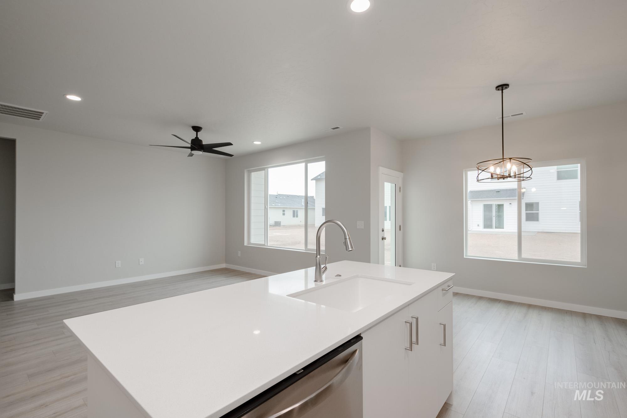 Kitchen featuring light wood-style flooring, hanging light fixtures, white cabinets, dishwasher, and recessed lighting