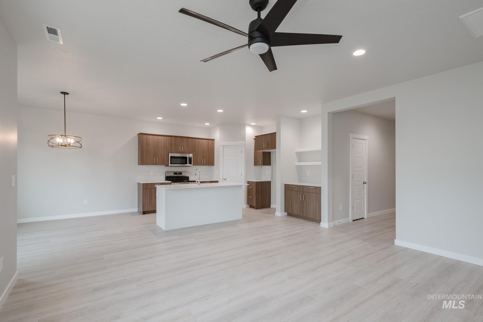 Kitchen with open floor plan, light wood-style floors, a center island with sink, a ceiling fan, and recessed lighting
