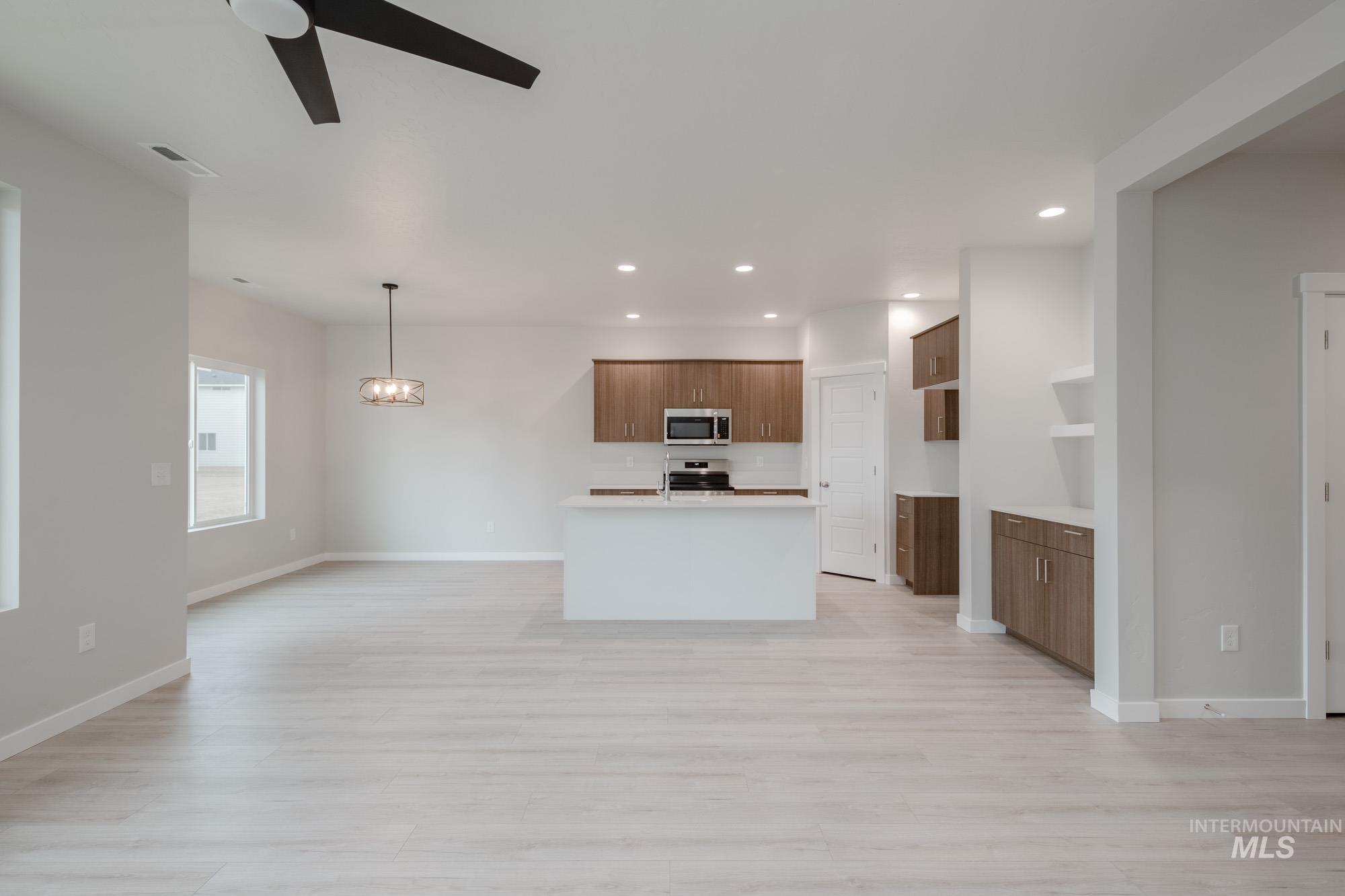 Kitchen featuring open floor plan, a center island with sink, recessed lighting, and light wood finished floors