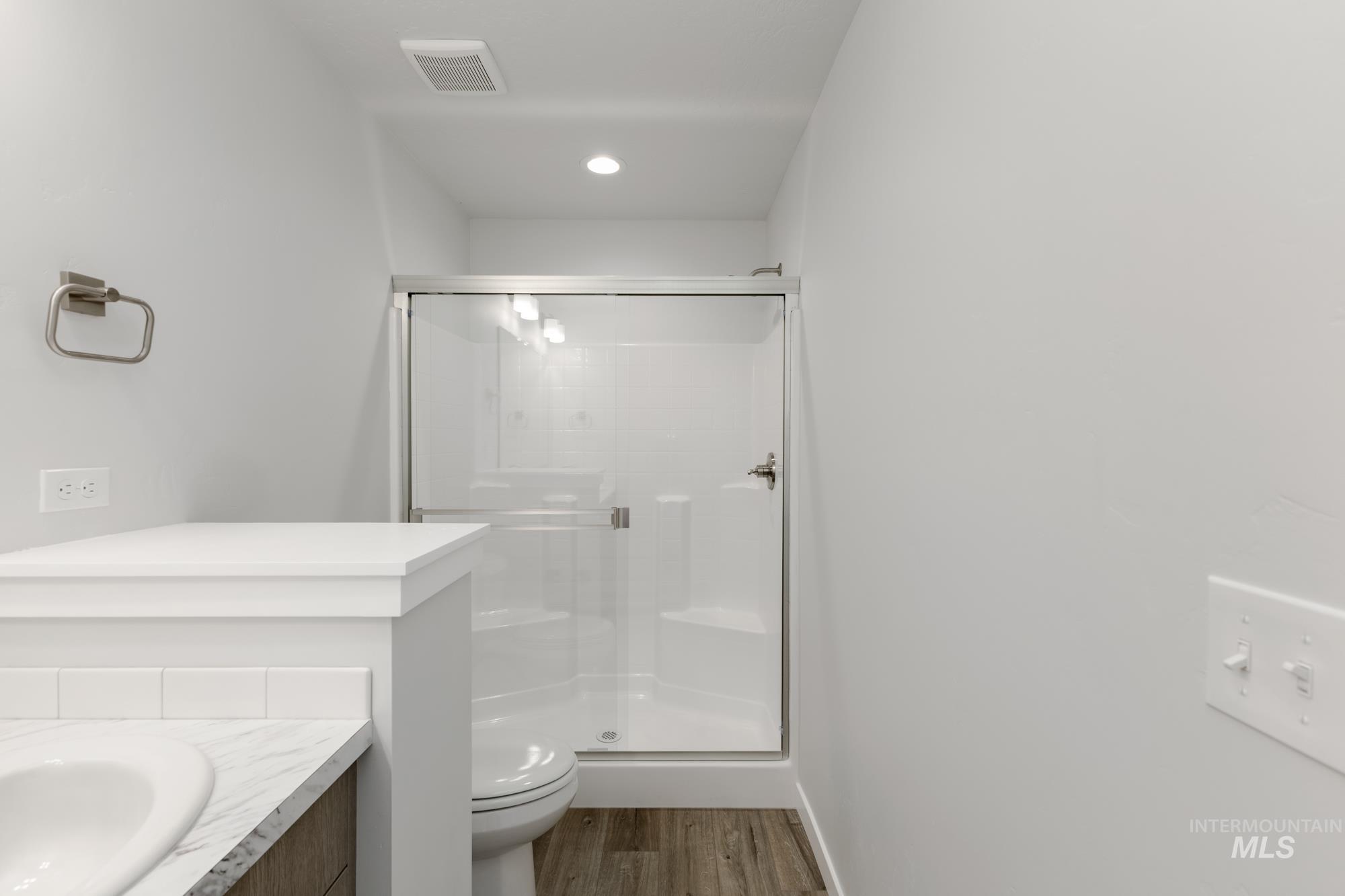 Full bath featuring vanity, dark wood-type flooring, a stall shower, and recessed lighting