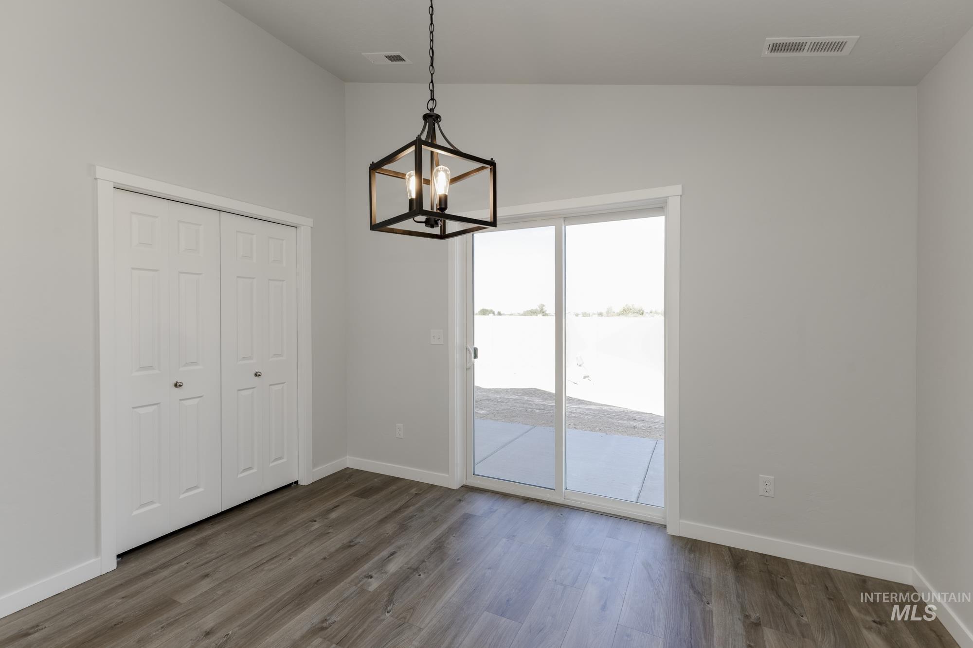 Unfurnished dining area with dark wood-type flooring, a chandelier, vaulted ceiling, and a water view