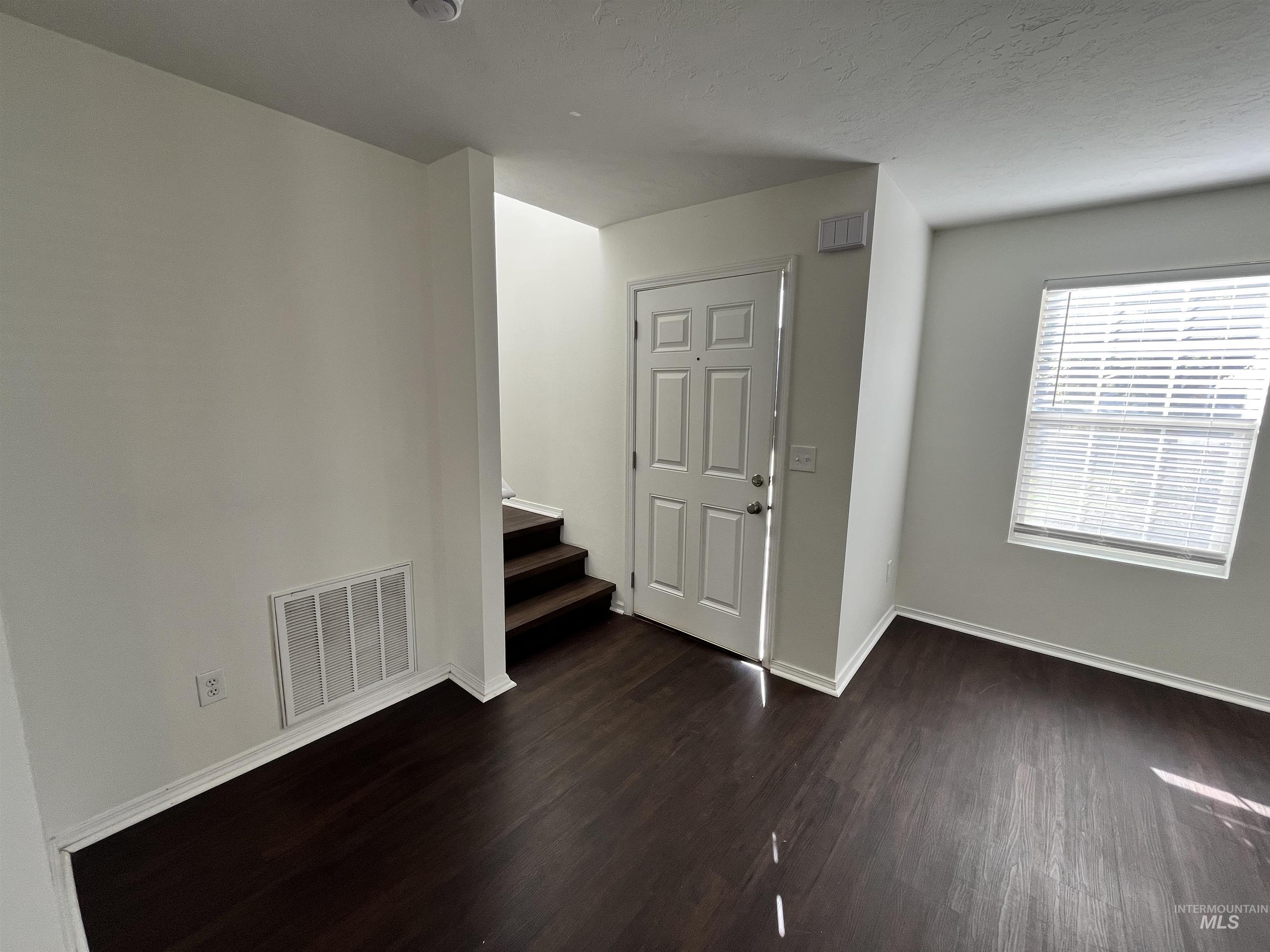 Spare room with dark wood-style floors and stairs