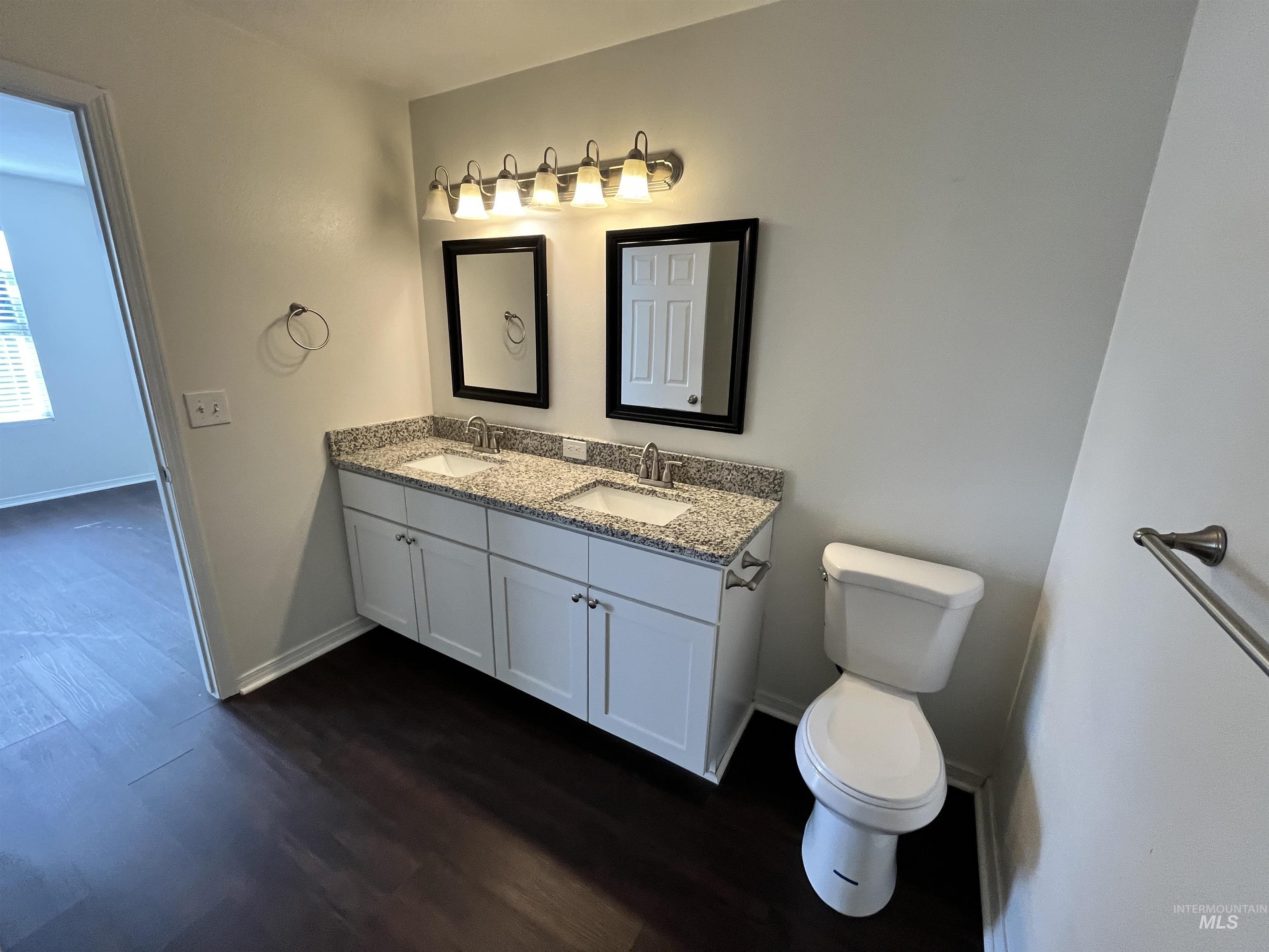 Full bath featuring dark wood-style flooring and double vanity