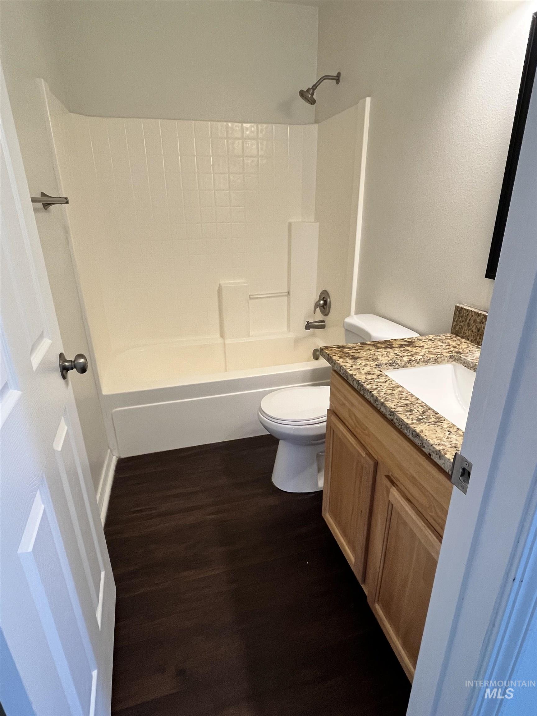 Bathroom featuring vanity, dark wood-type flooring, and shower / bathtub combination