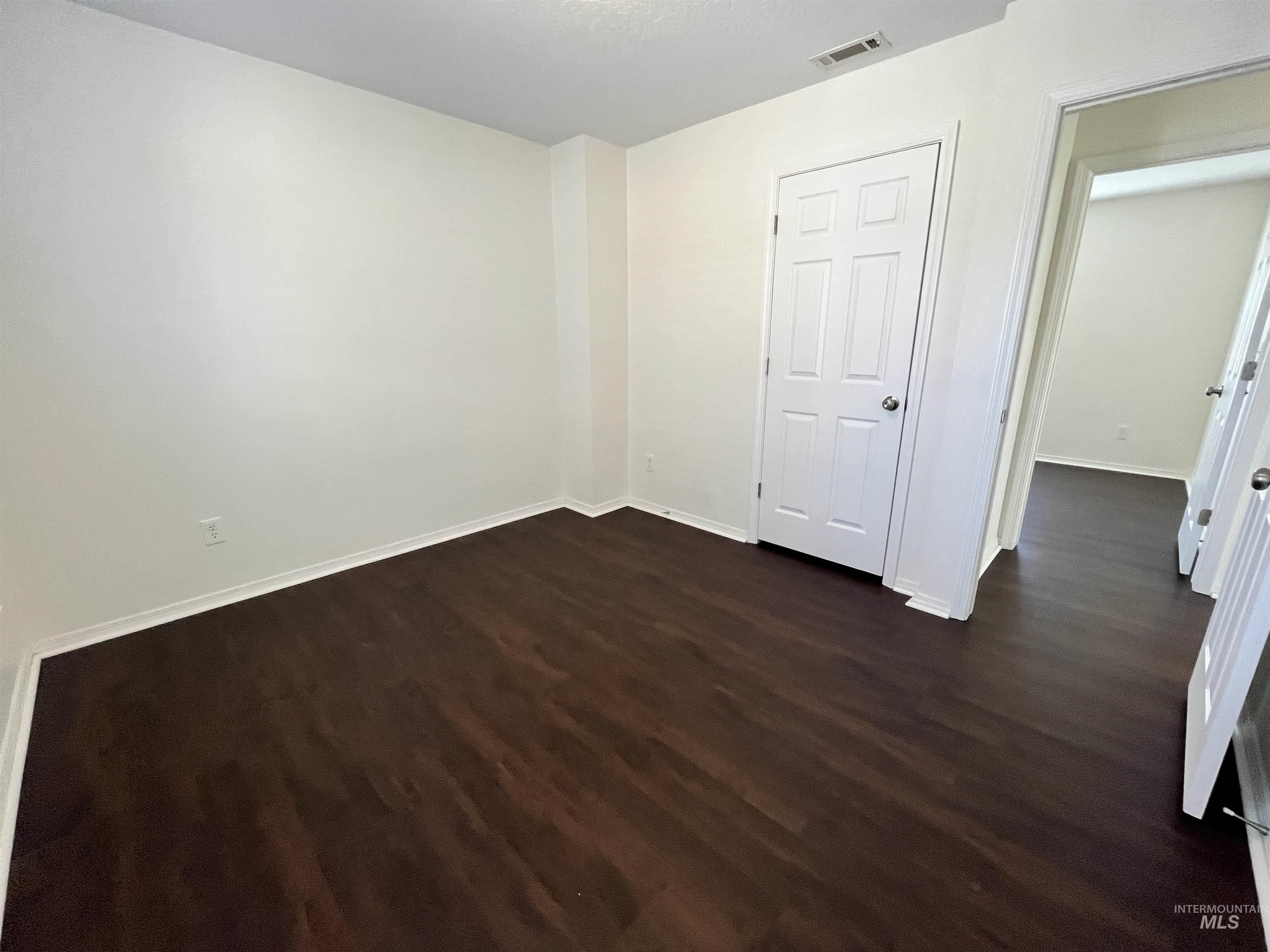 Unfurnished bedroom featuring dark wood-style flooring and baseboards