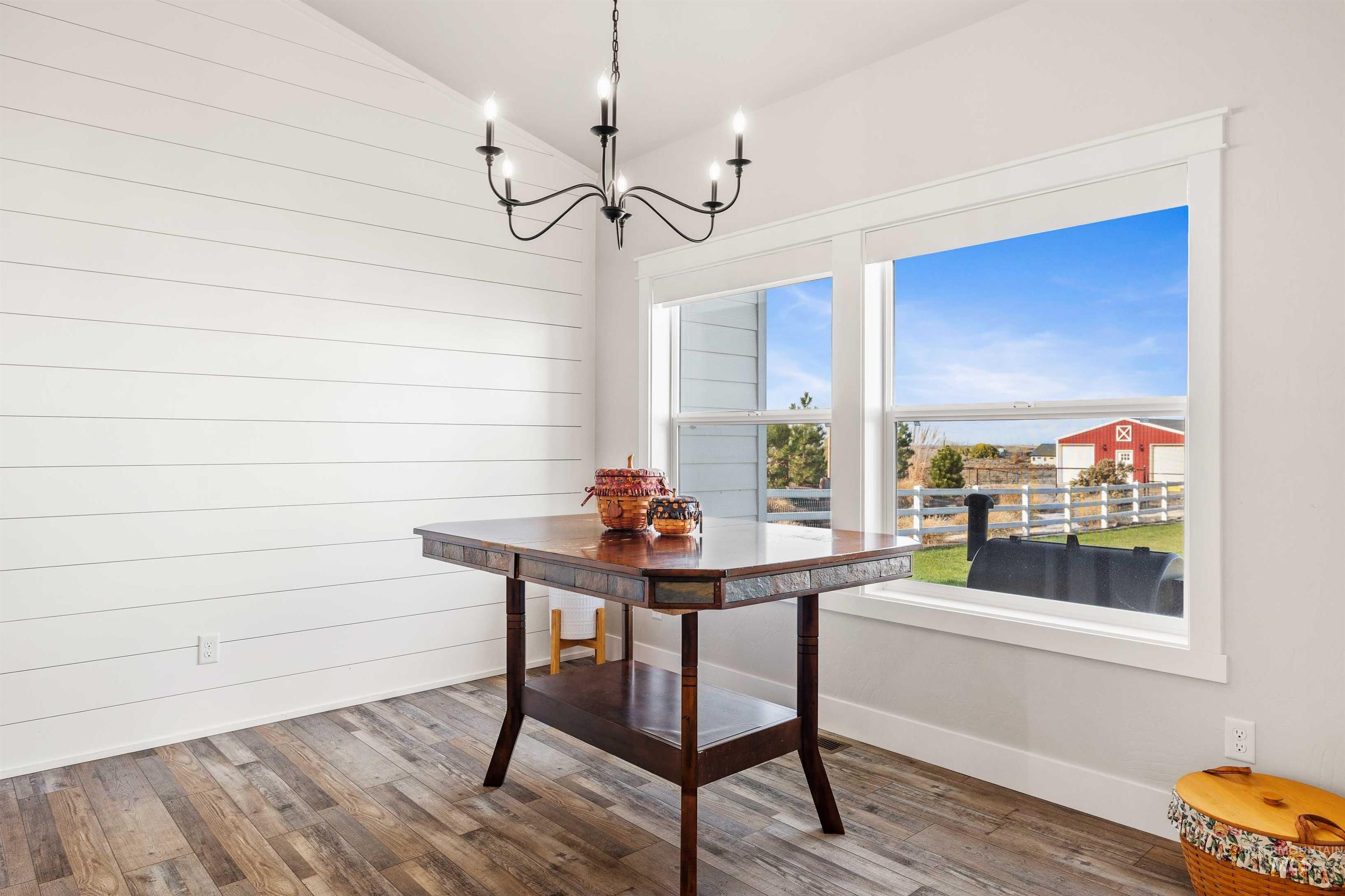 Dining space featuring wood finished floors, vaulted ceiling, and a chandelier