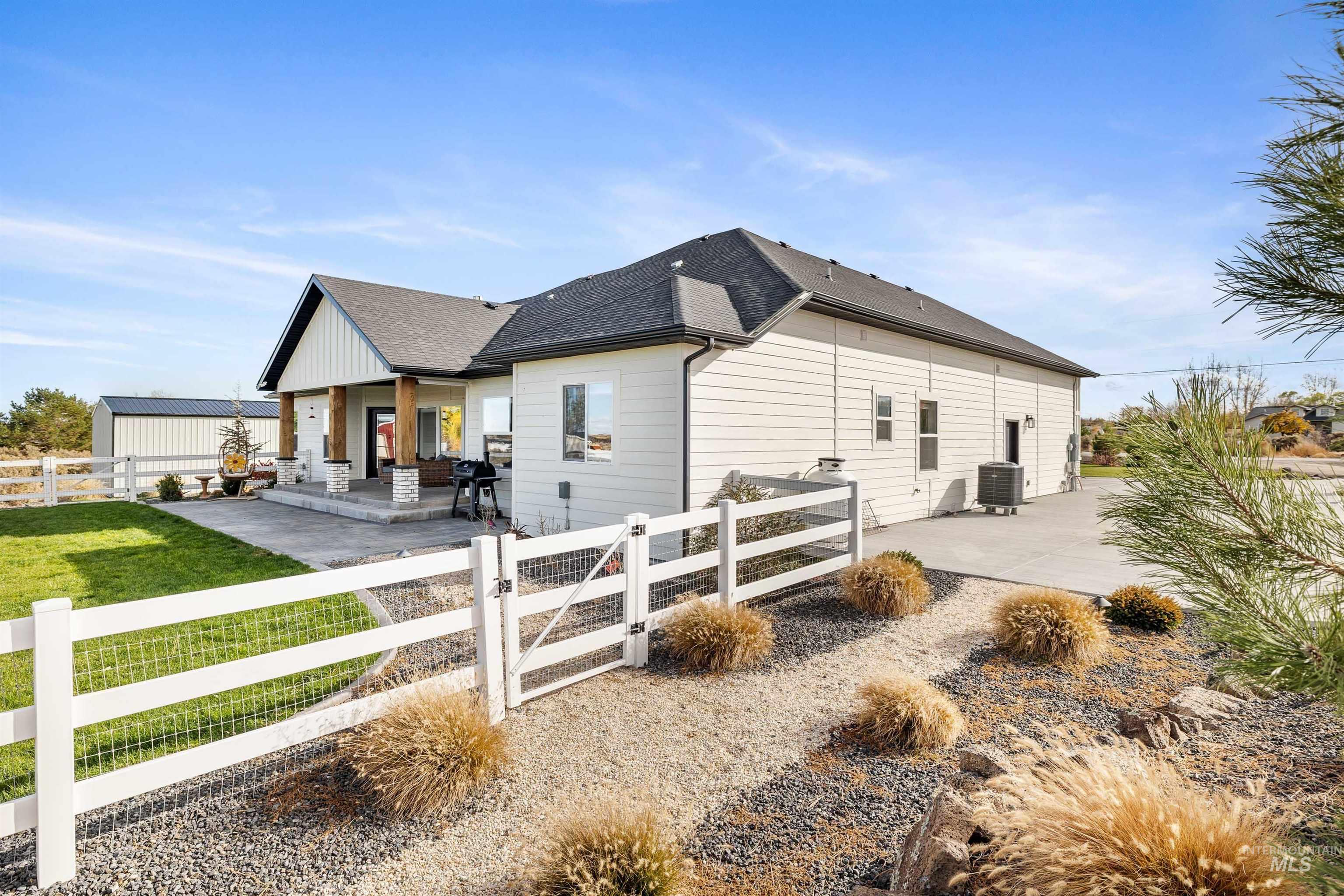 View of property exterior with a gate, a shingled roof, a fenced front yard, and a porch