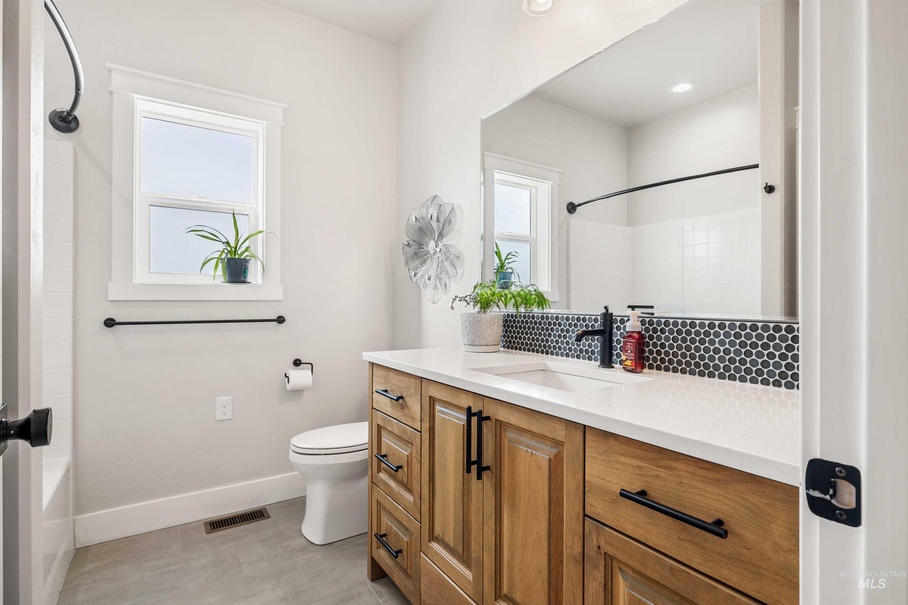 Full bathroom with vanity, decorative backsplash, and shower / bathtub combination