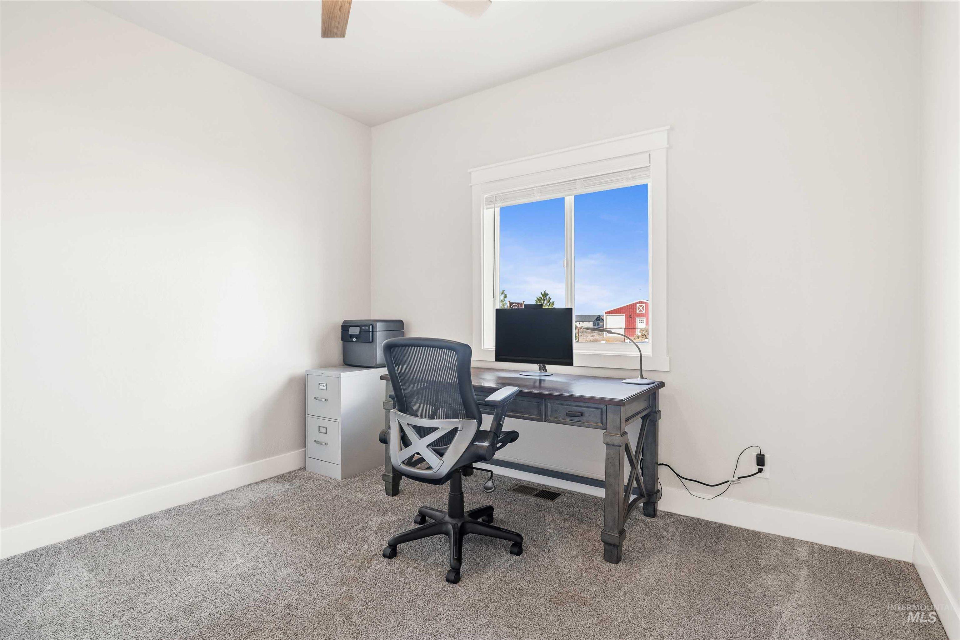 Carpeted office featuring baseboards and a ceiling fan