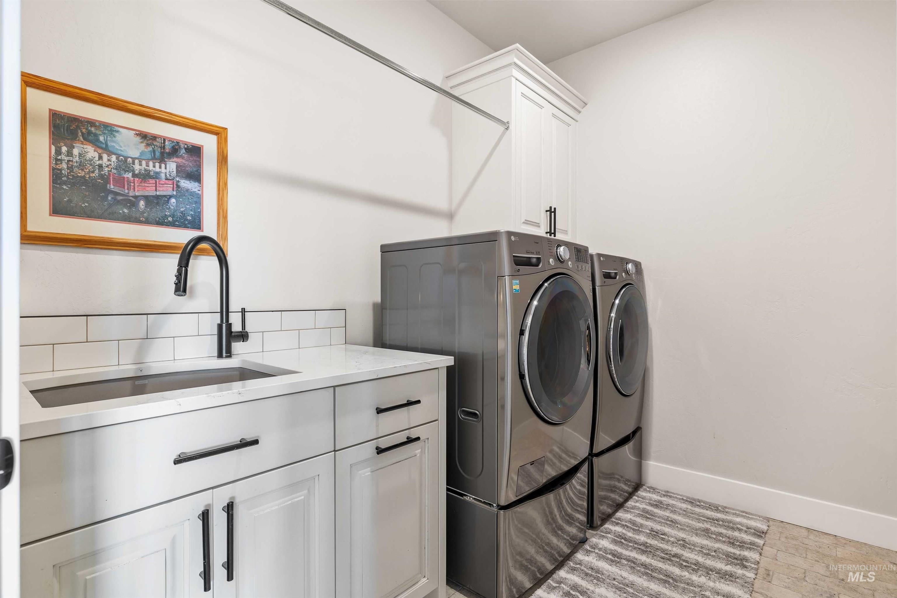 Washroom with cabinet space and washing machine and clothes dryer