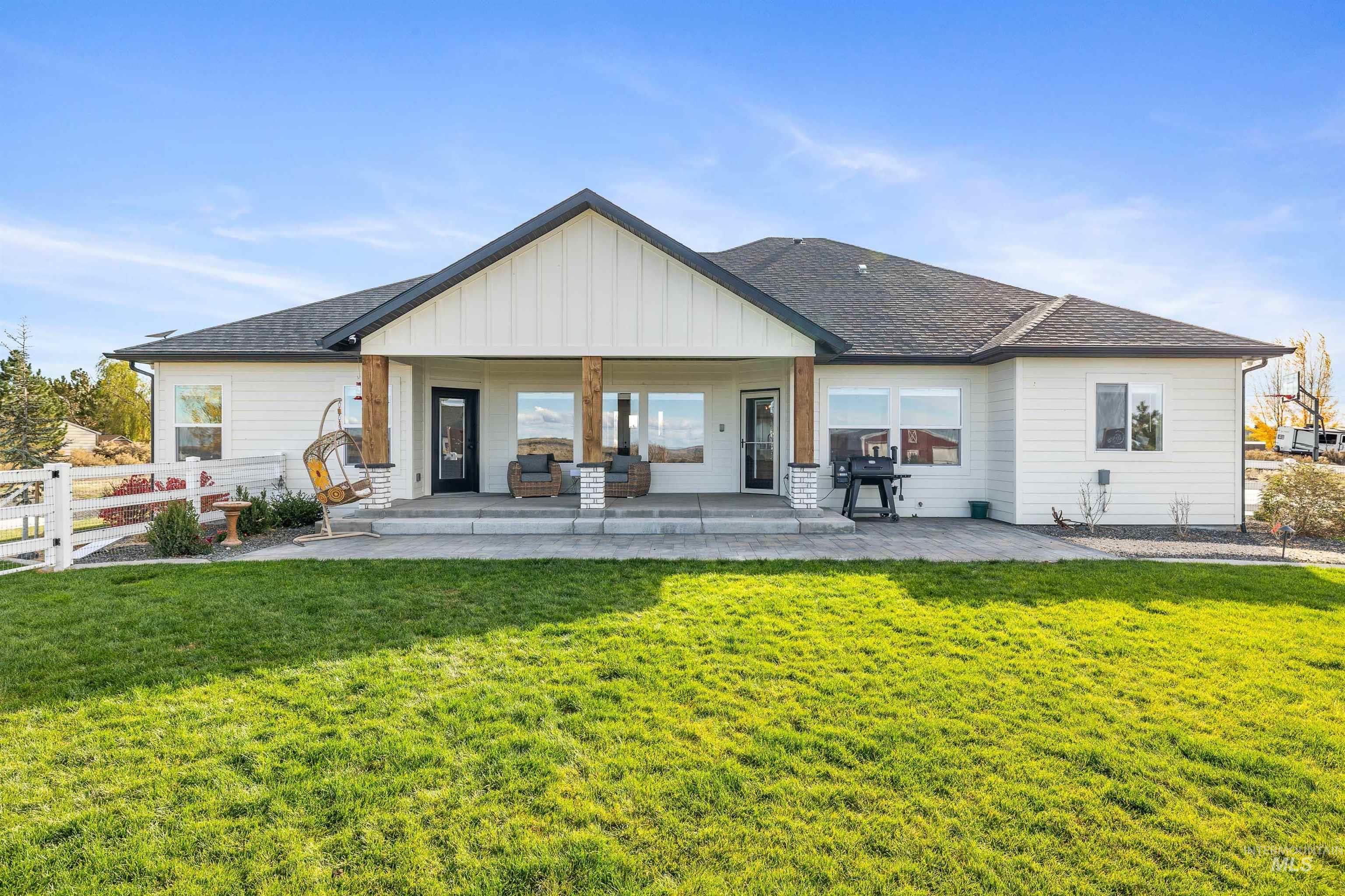 Rear view of property featuring board and batten siding, a shingled roof, and a patio area