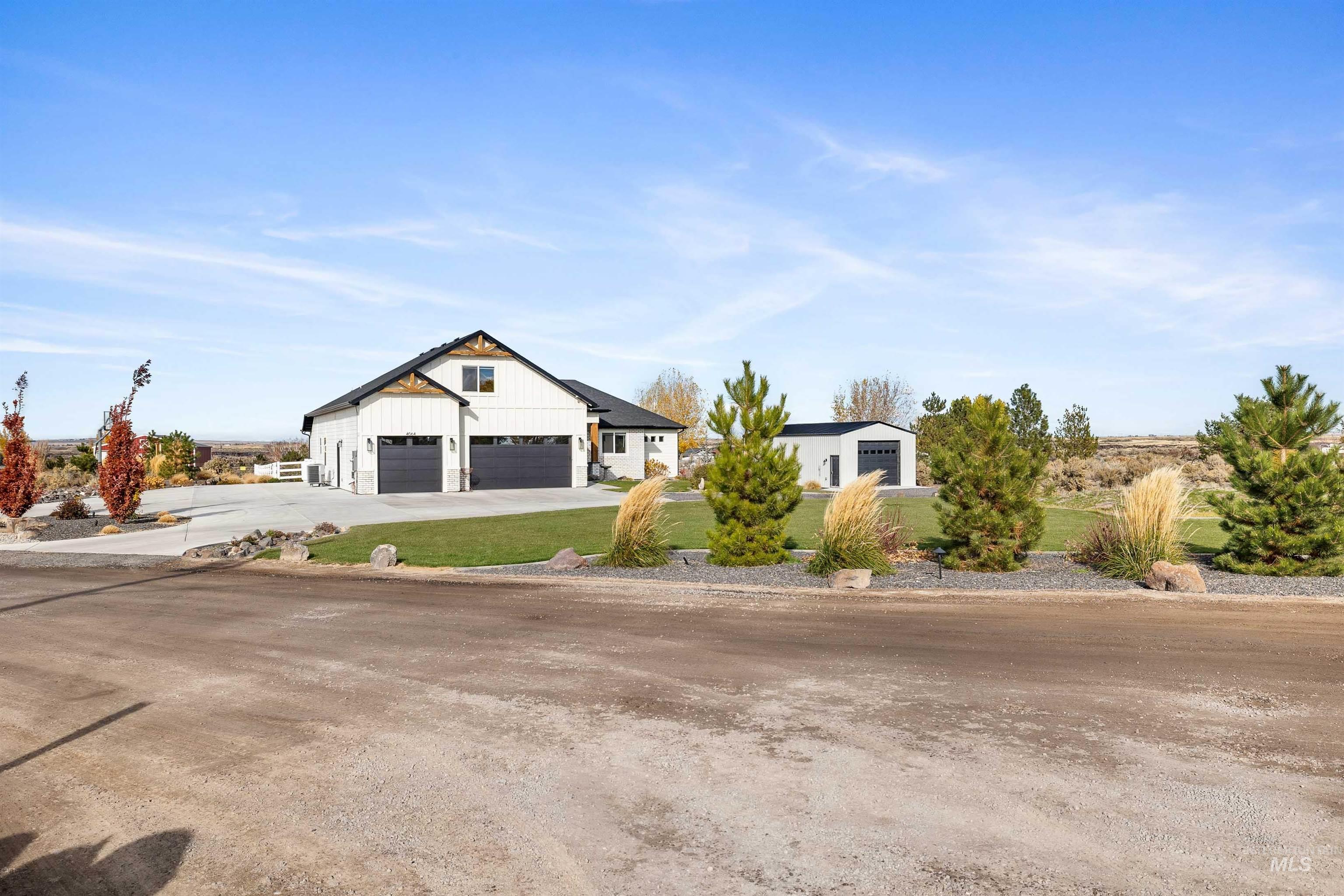 Modern inspired farmhouse featuring a garage, a front lawn, concrete driveway, and board and batten siding