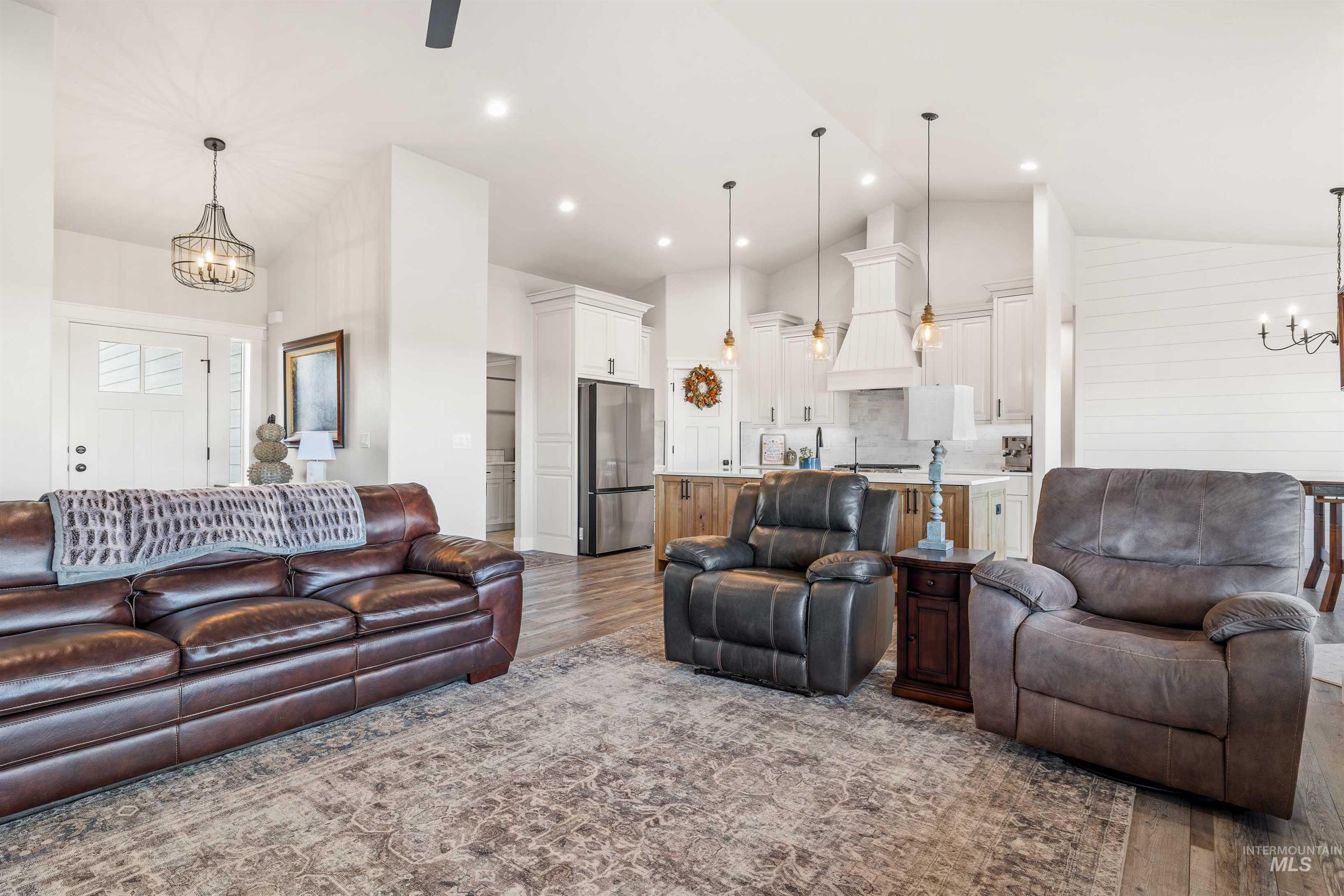 Living area featuring a chandelier, wood finished floors, high vaulted ceiling, recessed lighting, and a ceiling fan