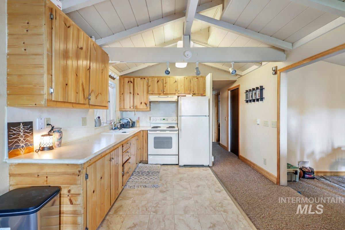Kitchen featuring white appliances, light countertops, decorative backsplash, light tile patterned flooring, and light brown cabinets