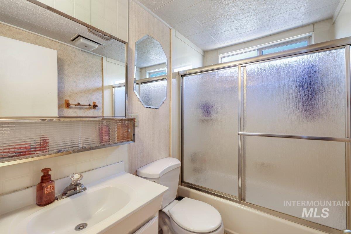 Bathroom featuring vanity and combined bath / shower with glass door