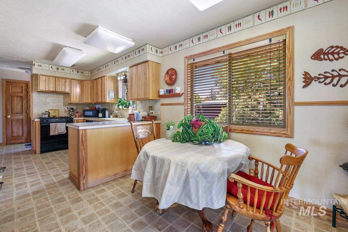 Kitchen with a peninsula, light countertops, black appliances, tasteful backsplash, and a textured ceiling