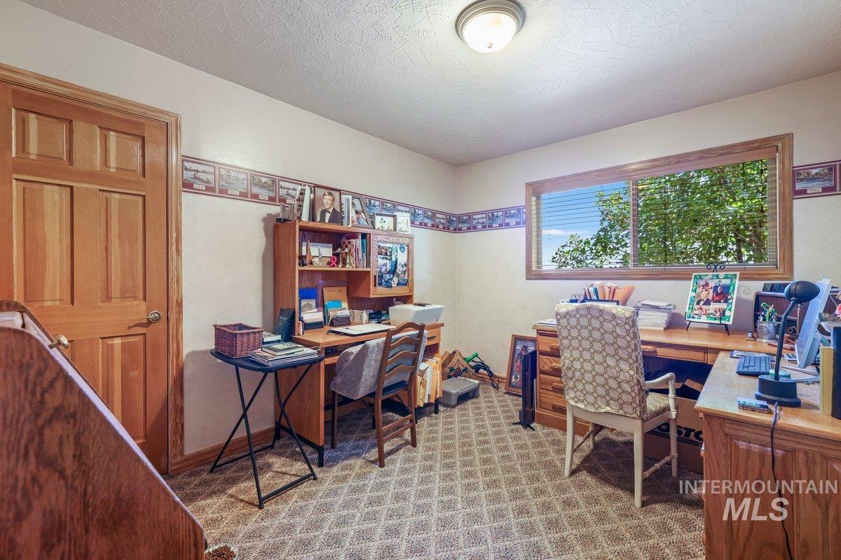 Office space with a textured ceiling and light carpet