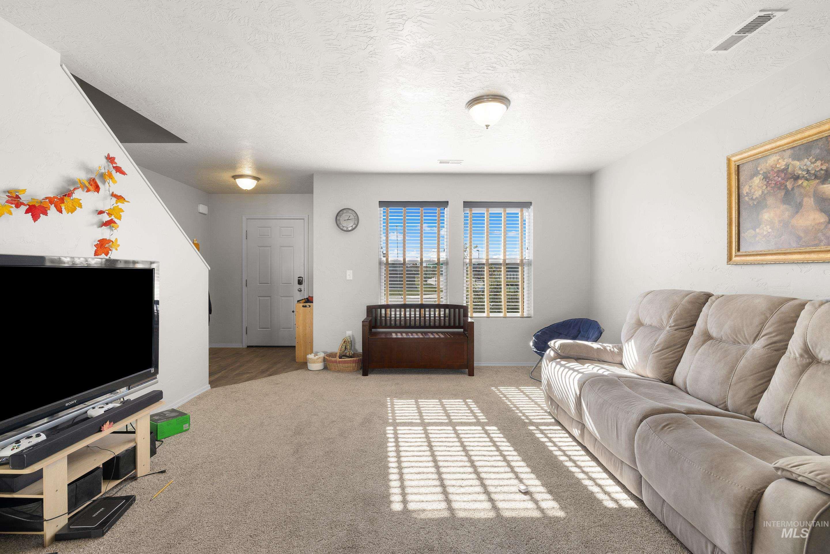 Living area featuring carpet floors and a textured ceiling