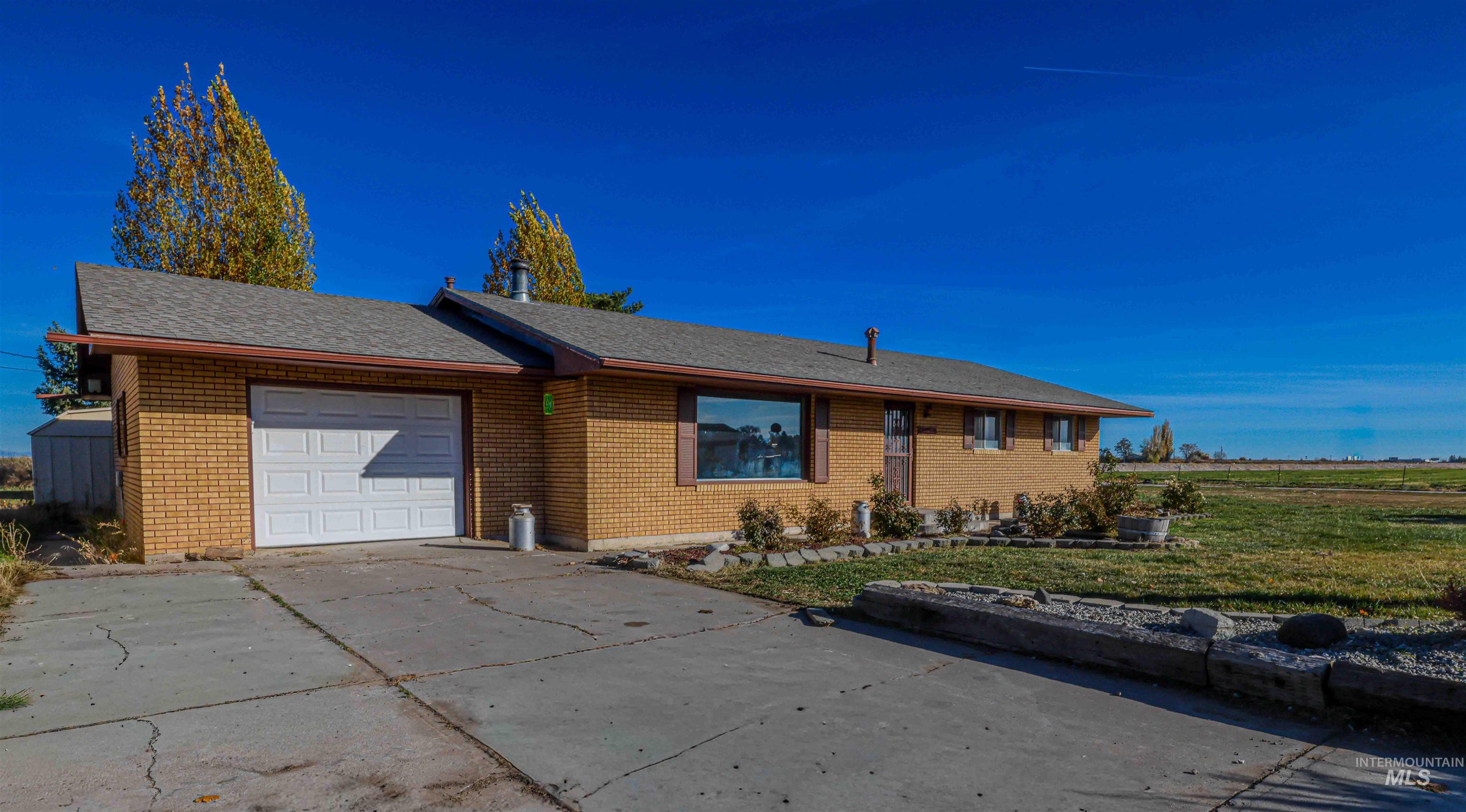 Ranch-style house featuring a garage, driveway, a shingled roof, and brick siding