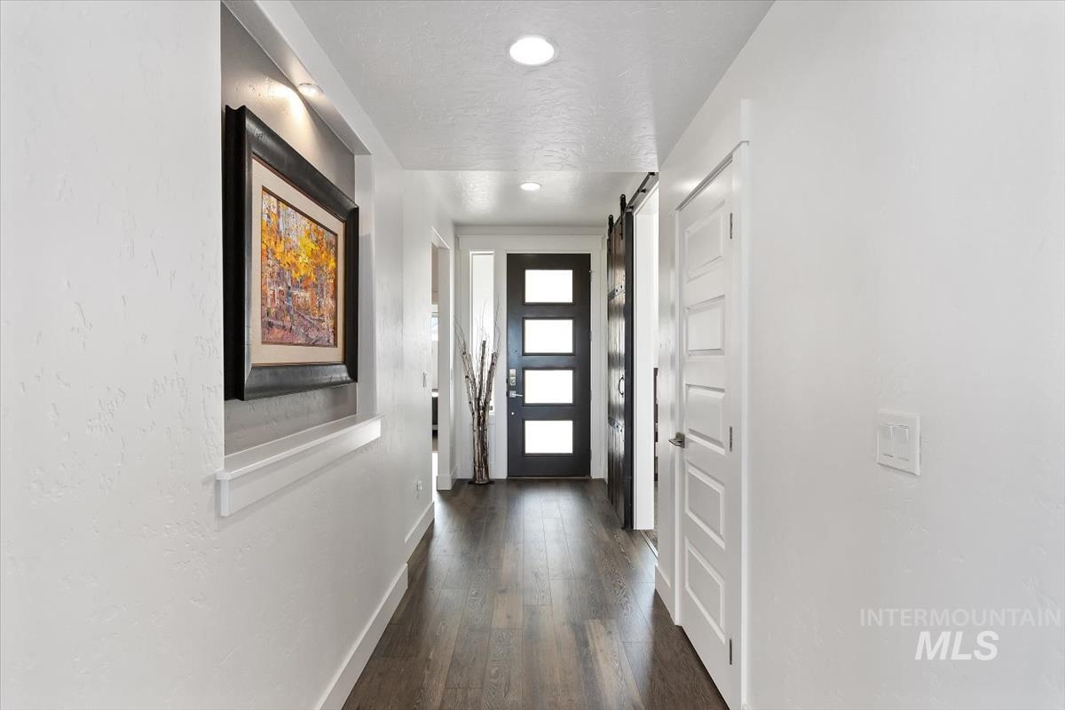 Doorway featuring a barn door, wood finished floors, a textured ceiling, and recessed lighting