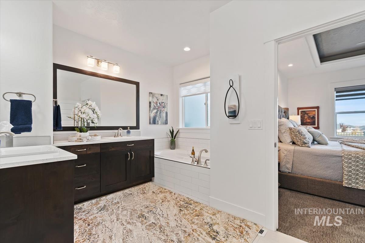 Bathroom featuring a bath, double vanity, connected bathroom, and recessed lighting